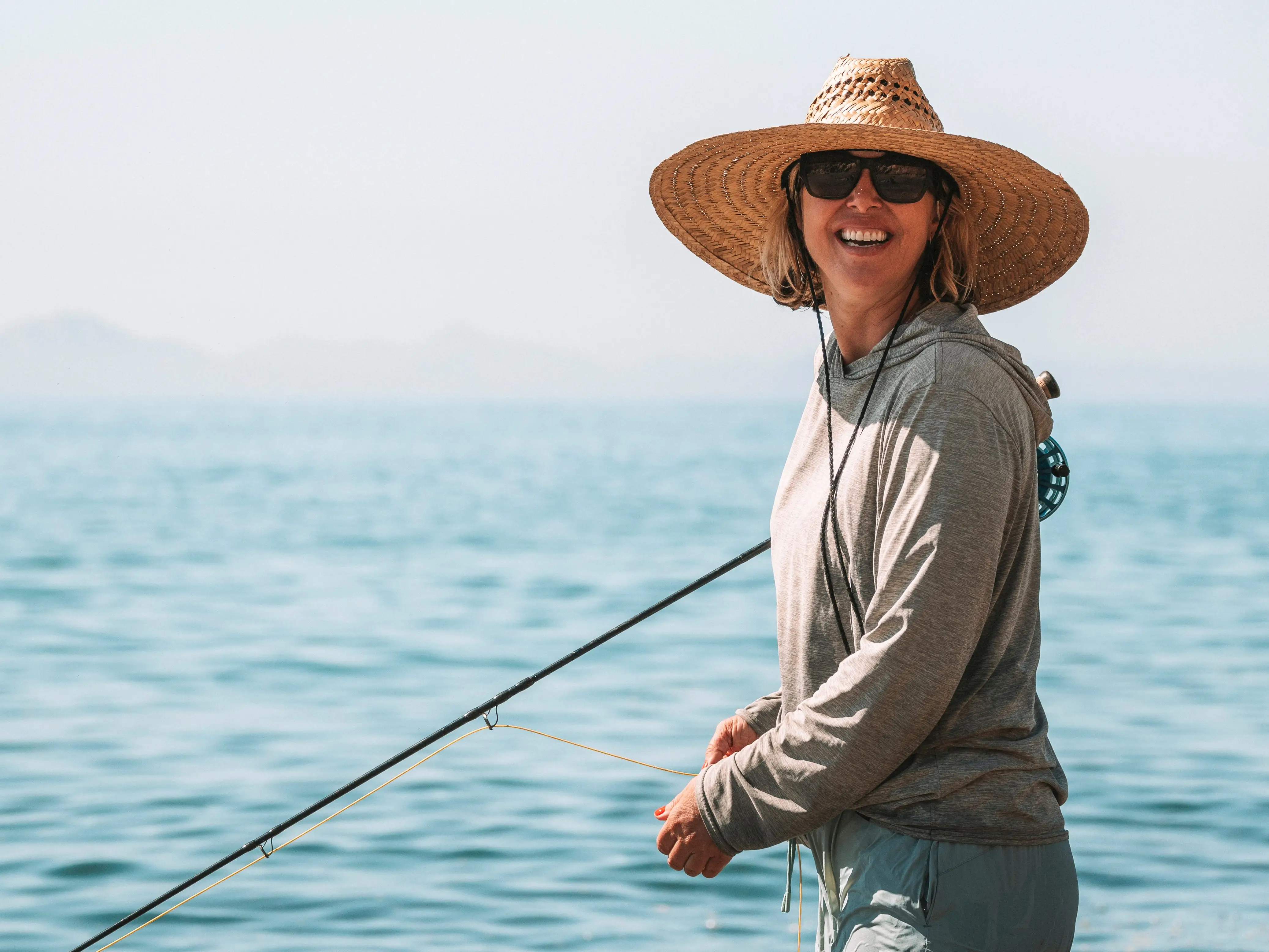 a woman wearing a hat by the ocean