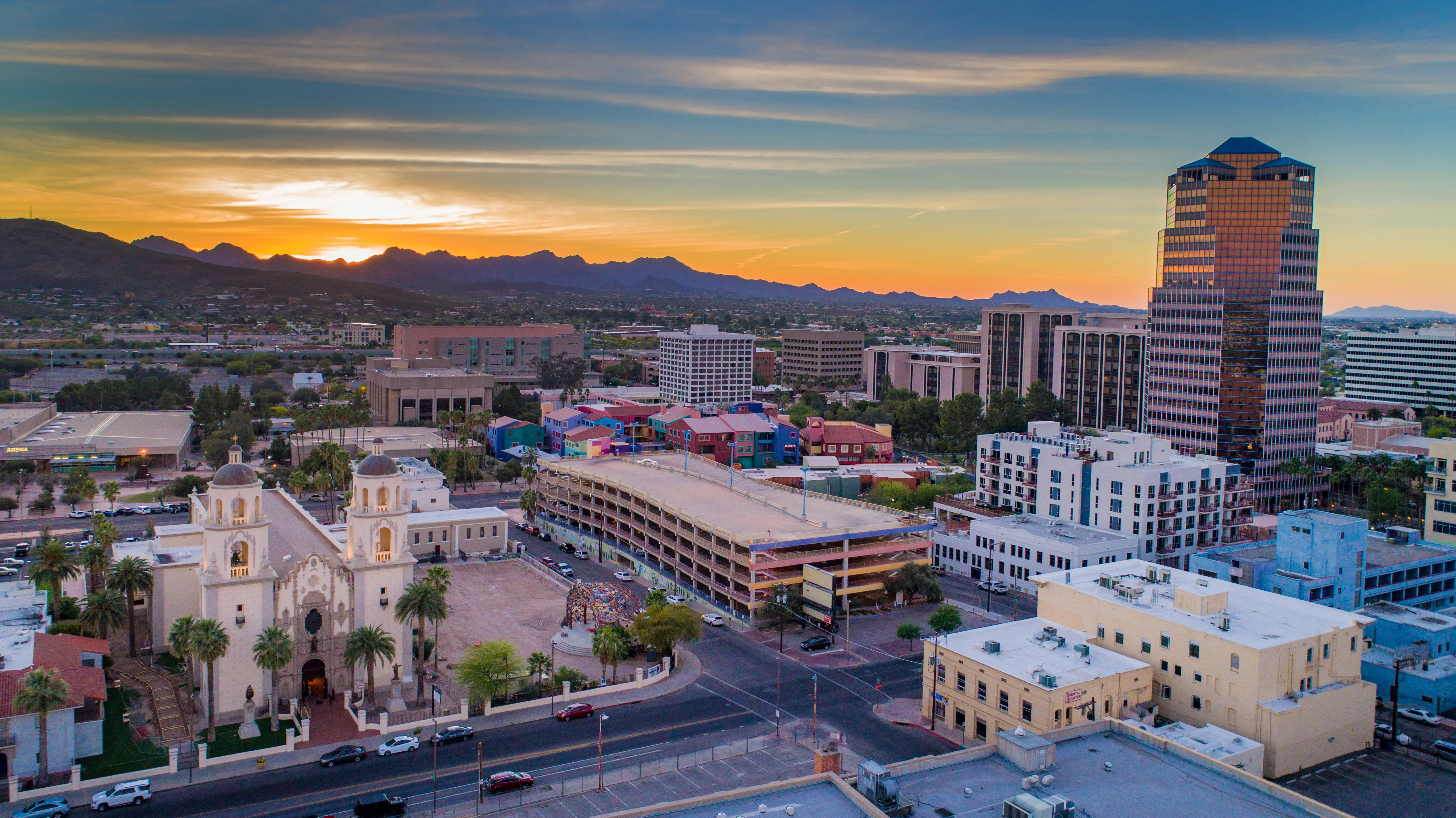 Downtown Tucson skyline at sunset with St. Augustine Cathedral, high-rise buildings, streets and mountains.