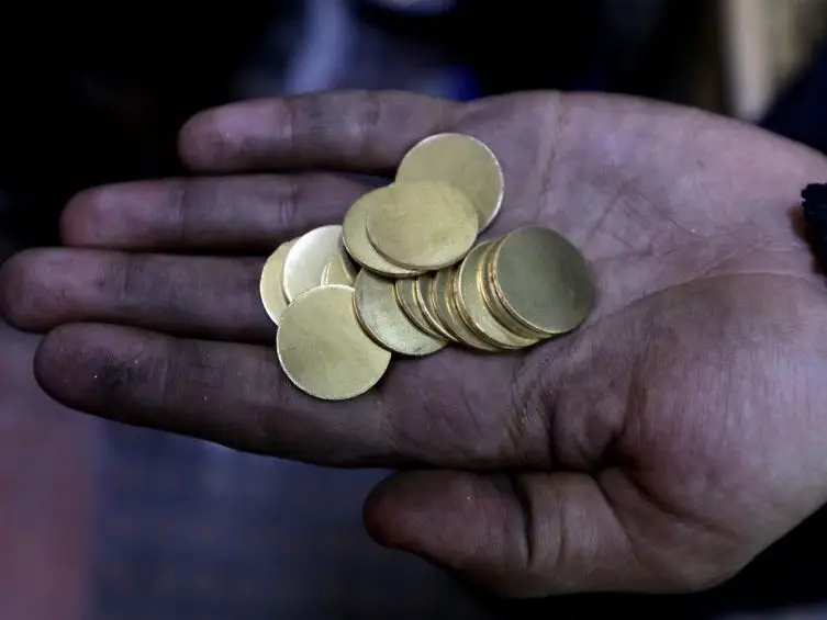 An outstretched palm of gold coins.
