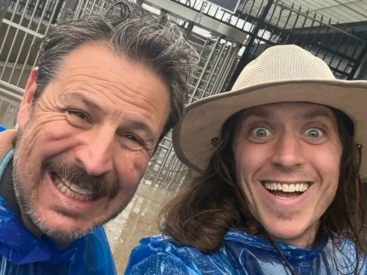Two men smiling in blue ponchos