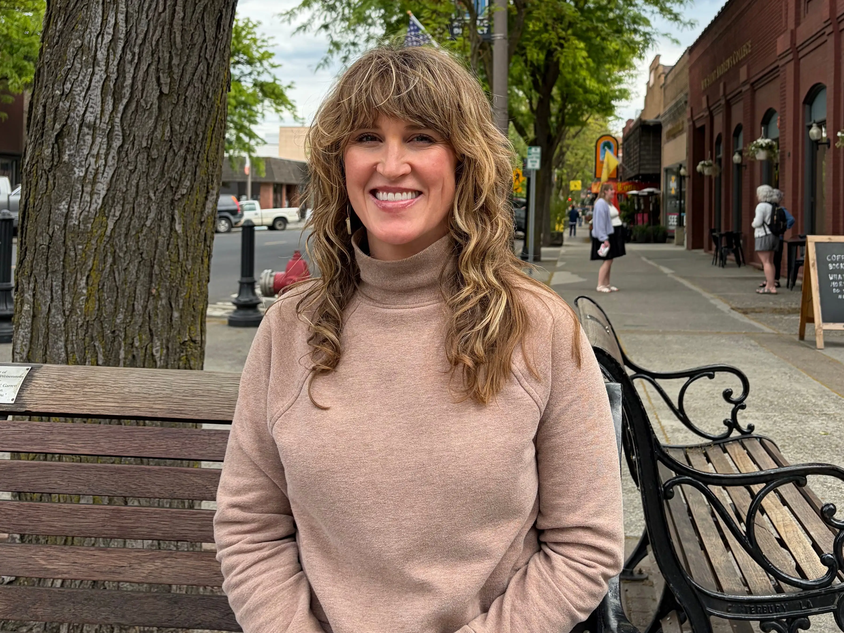Stacy sits on a bench on a downtown street.