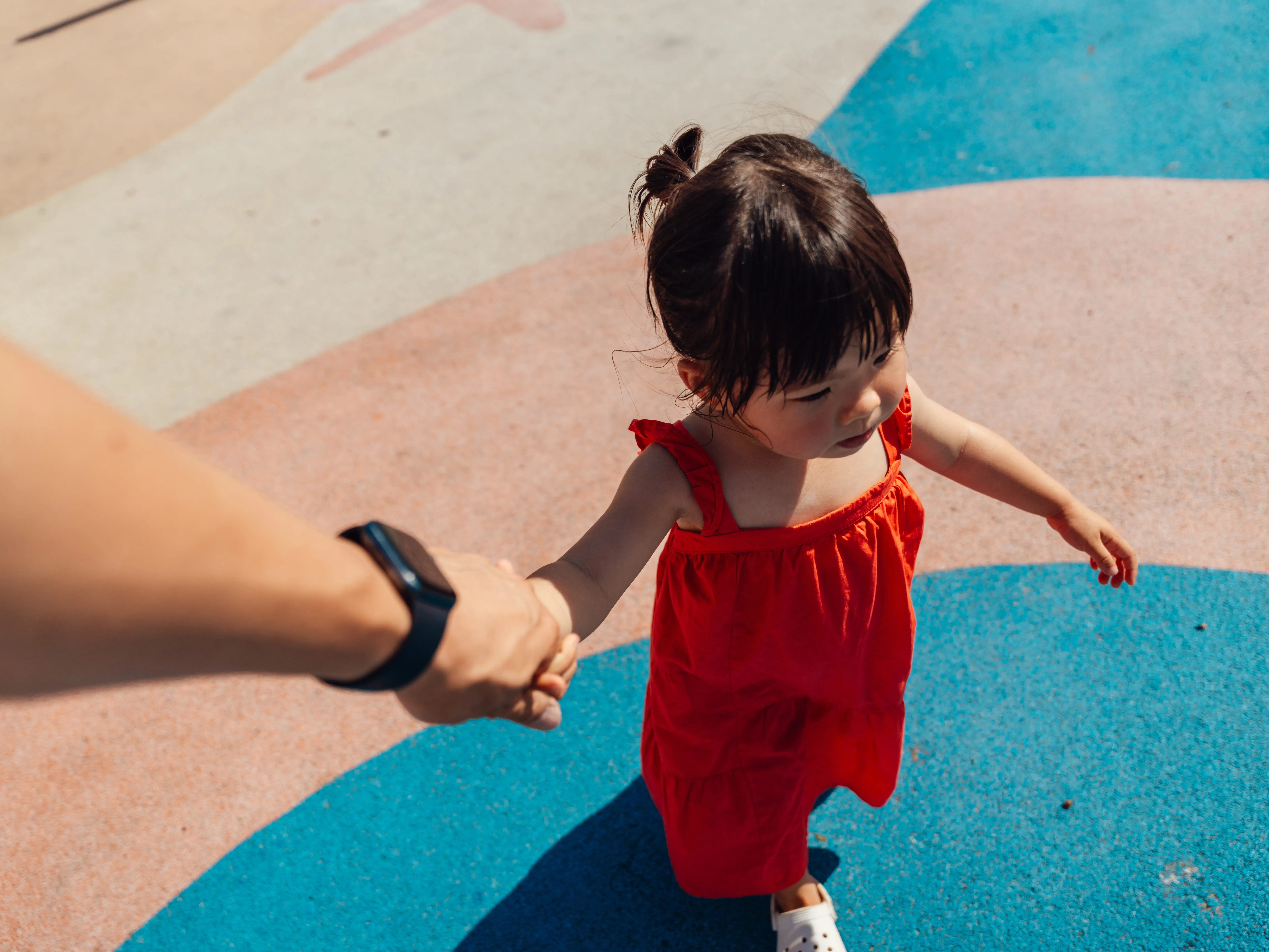 A little girl holding hands with parent