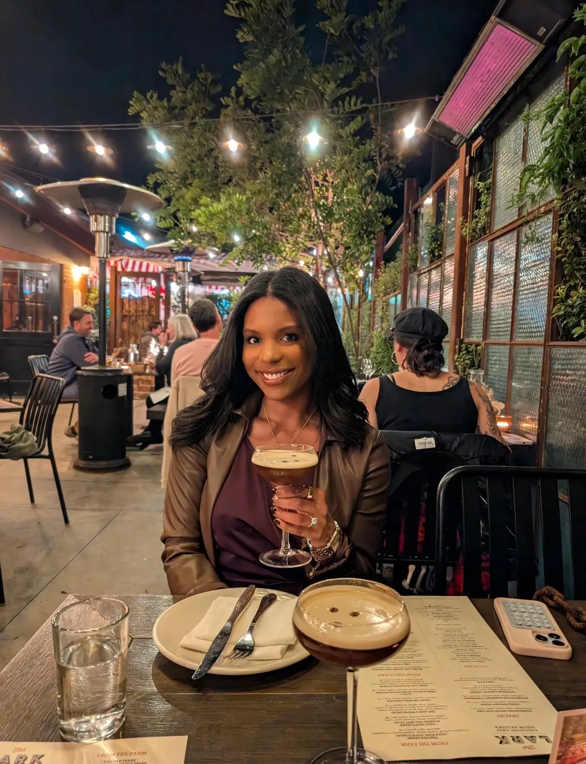 A woman posing with an espresso martini at a restaurant.