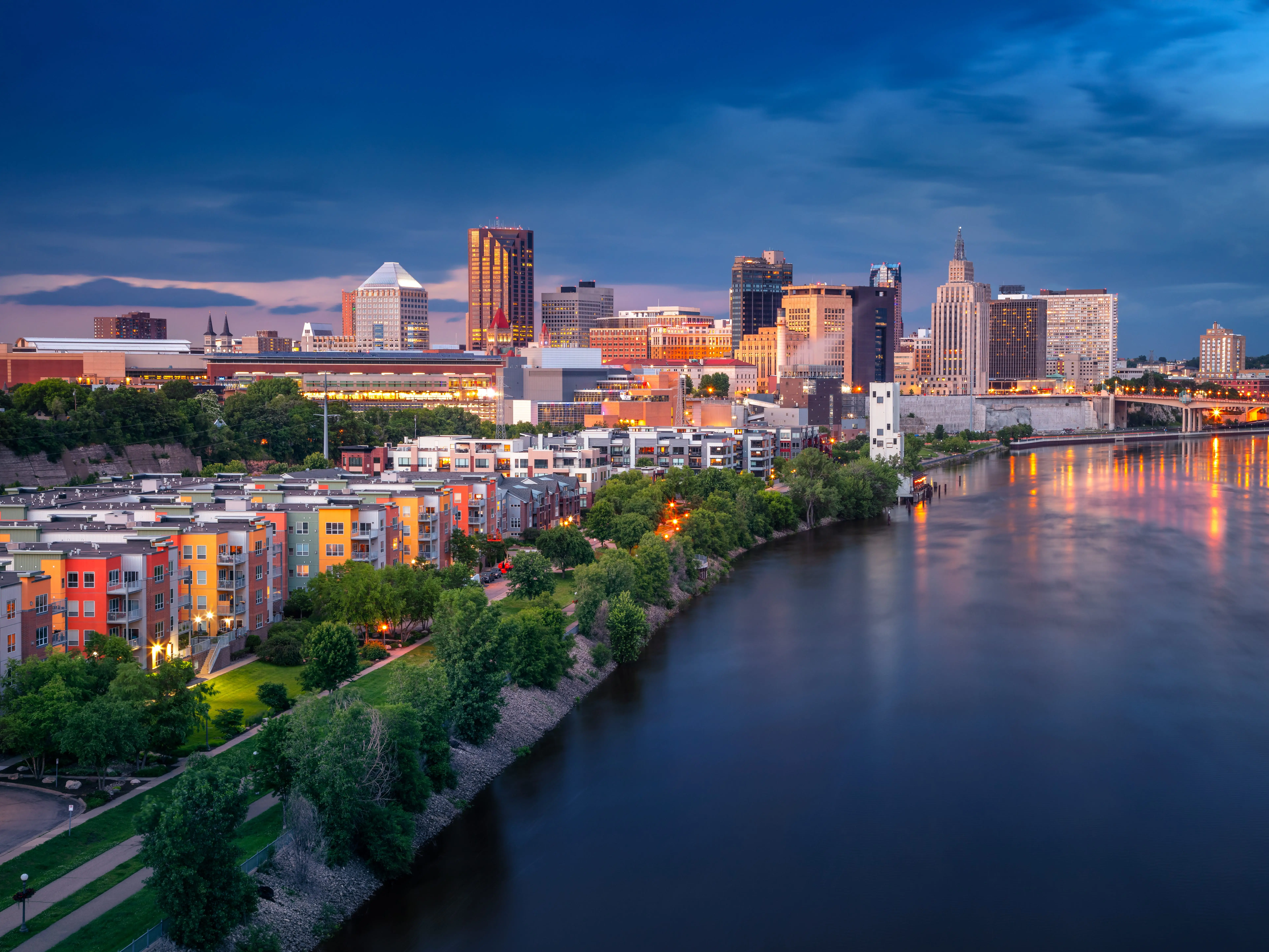 Aerial cityscape image of downtown St. Paul, Minnesota, USA with reflection of the skyline in Mississippi River at stormy summer sunset.