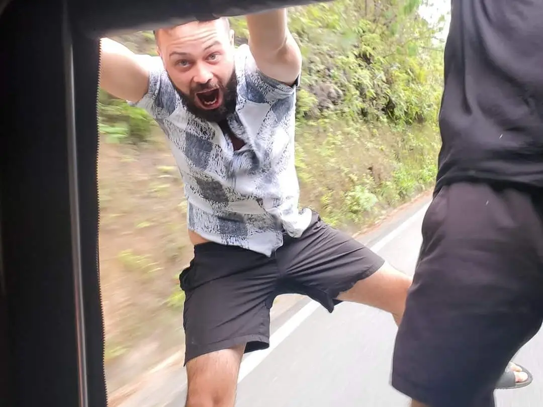 A man hanging on the back of a truck.