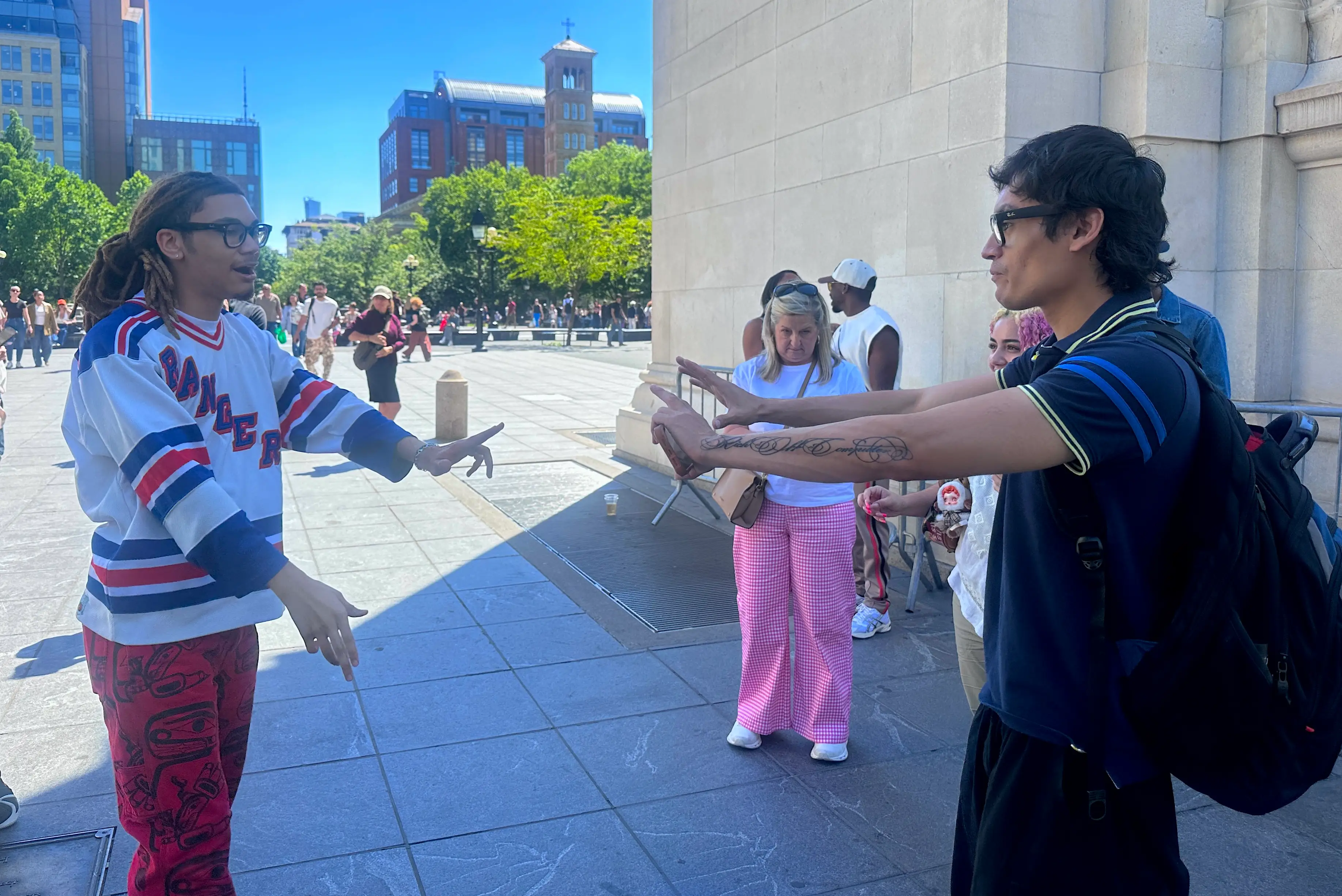 Two men in Washington Square Park point at each other. One is wearing Meta Ray-Ban glasses.