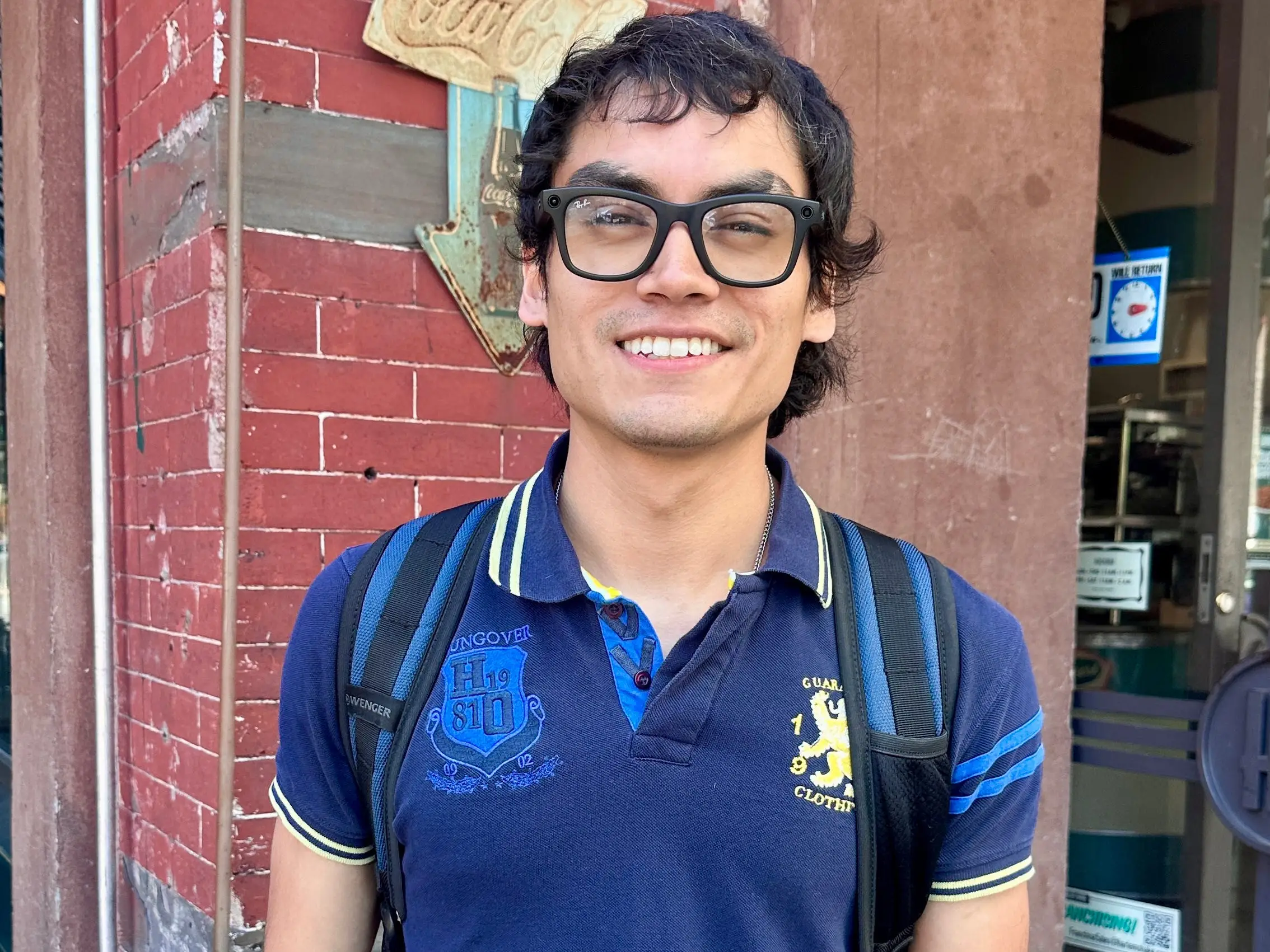 A man in Meta Ray-Bans and a blue shirt, wearing a backpack.