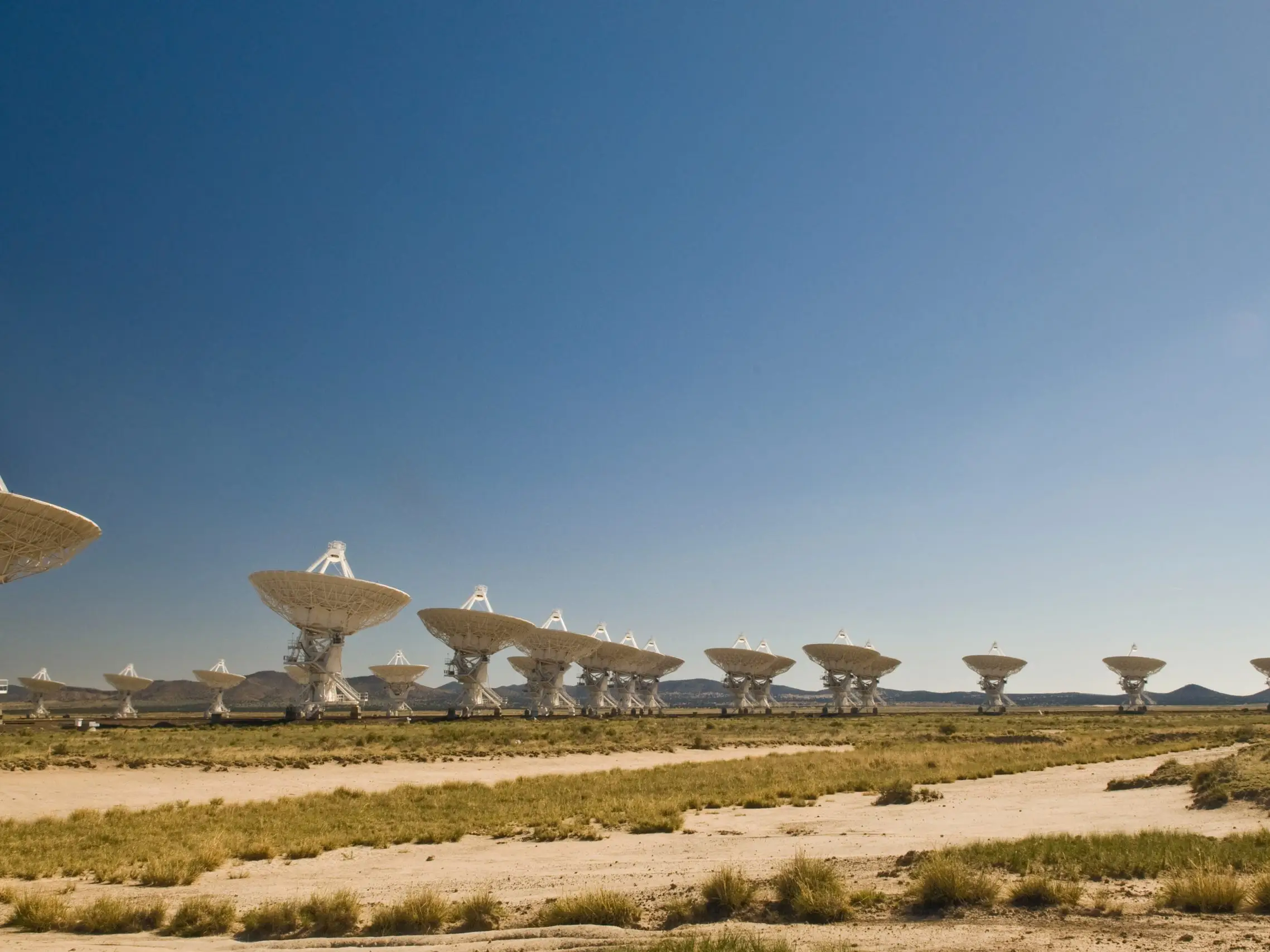 Many of the 27 radio telescopes arranged in close formation on railroad tracks on the Plains of San Augustin, near Socorro, New Mexico