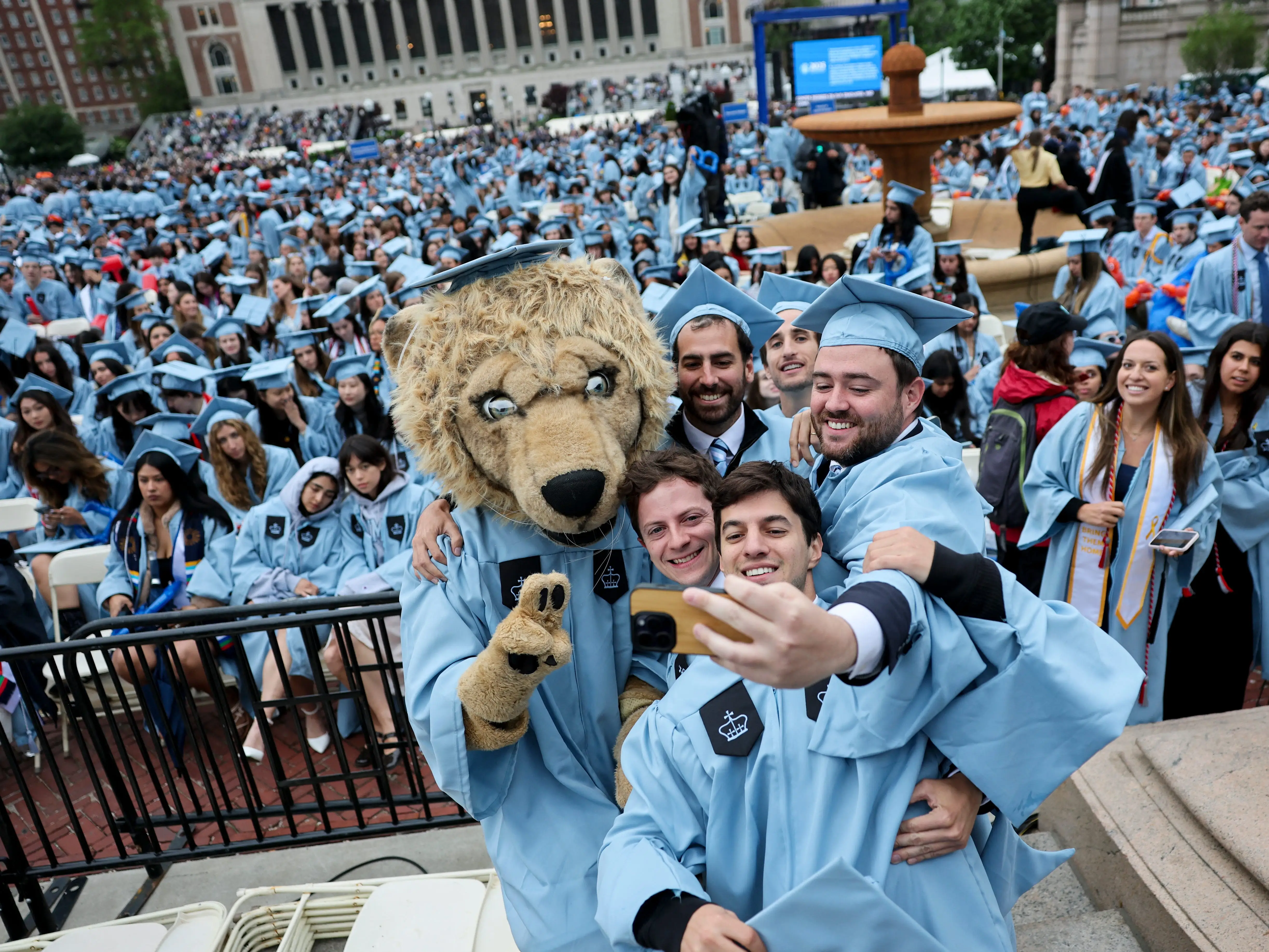 Students pose with a person dressed as Roar-ee the Lion mascot, before the Commencement Ceremony at Columbia University in New York on May 21, 2025,
