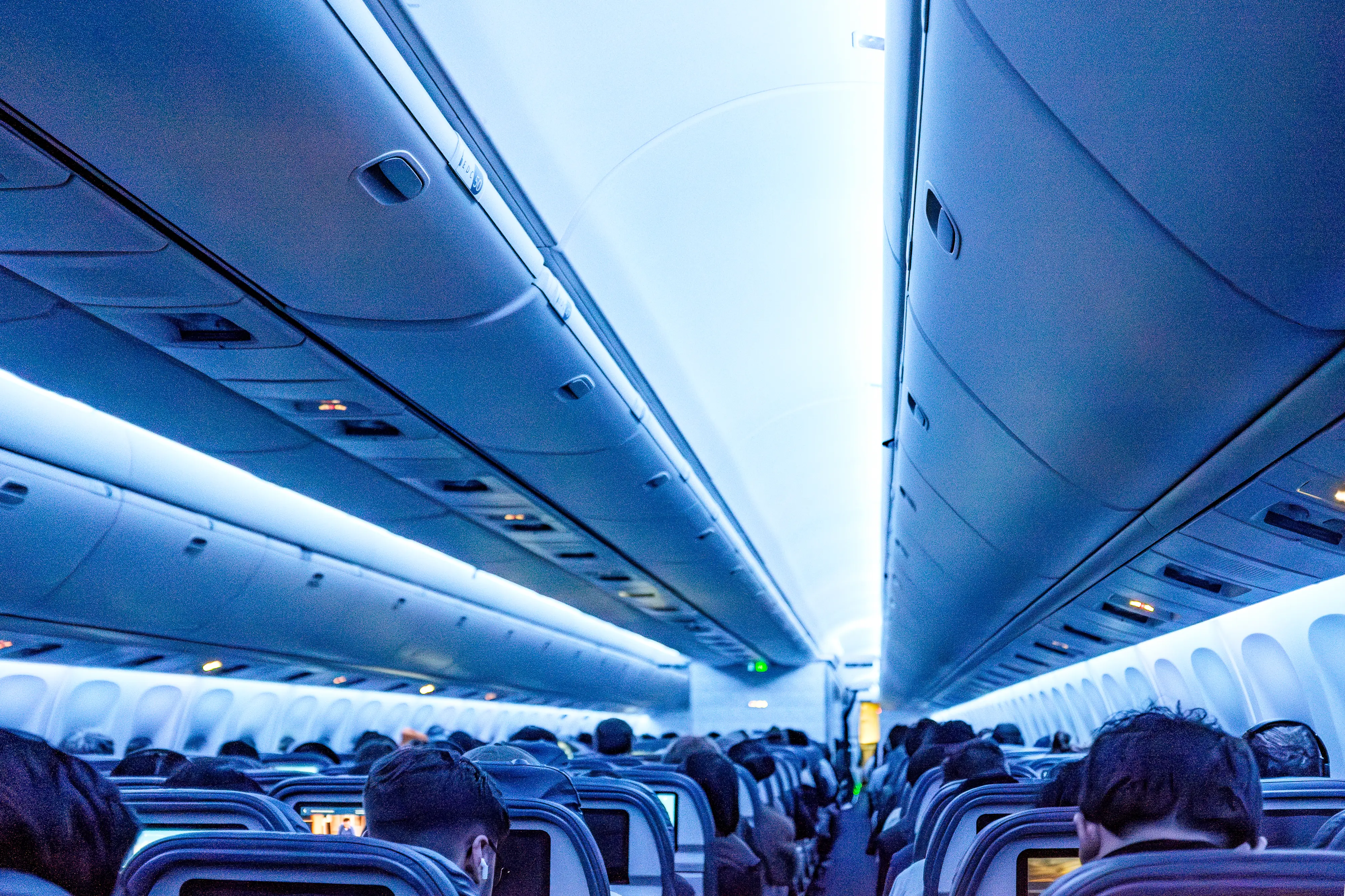 Inside a large plane cabin with dim, blue lights
