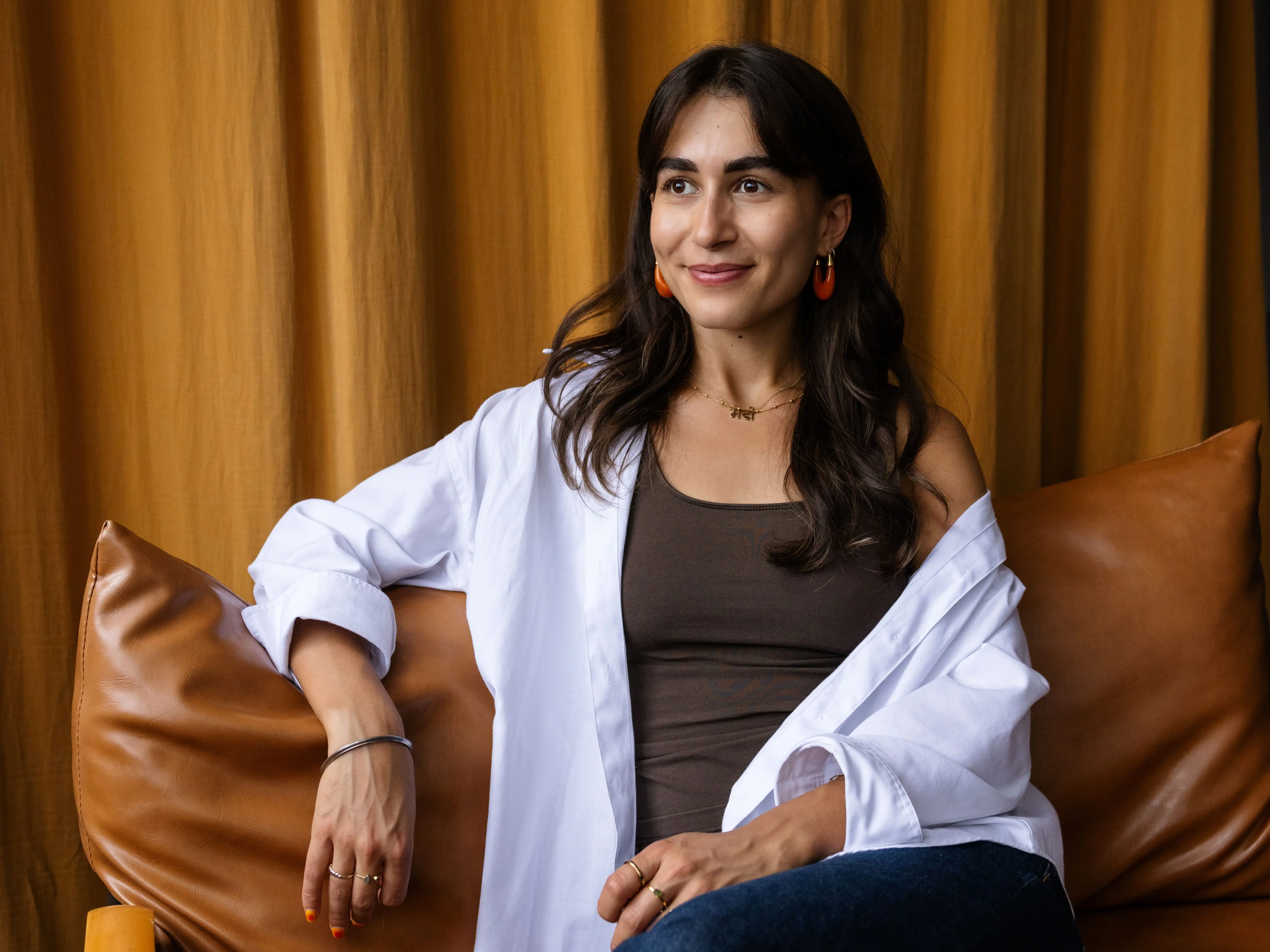 A woman sits on a leather couch.