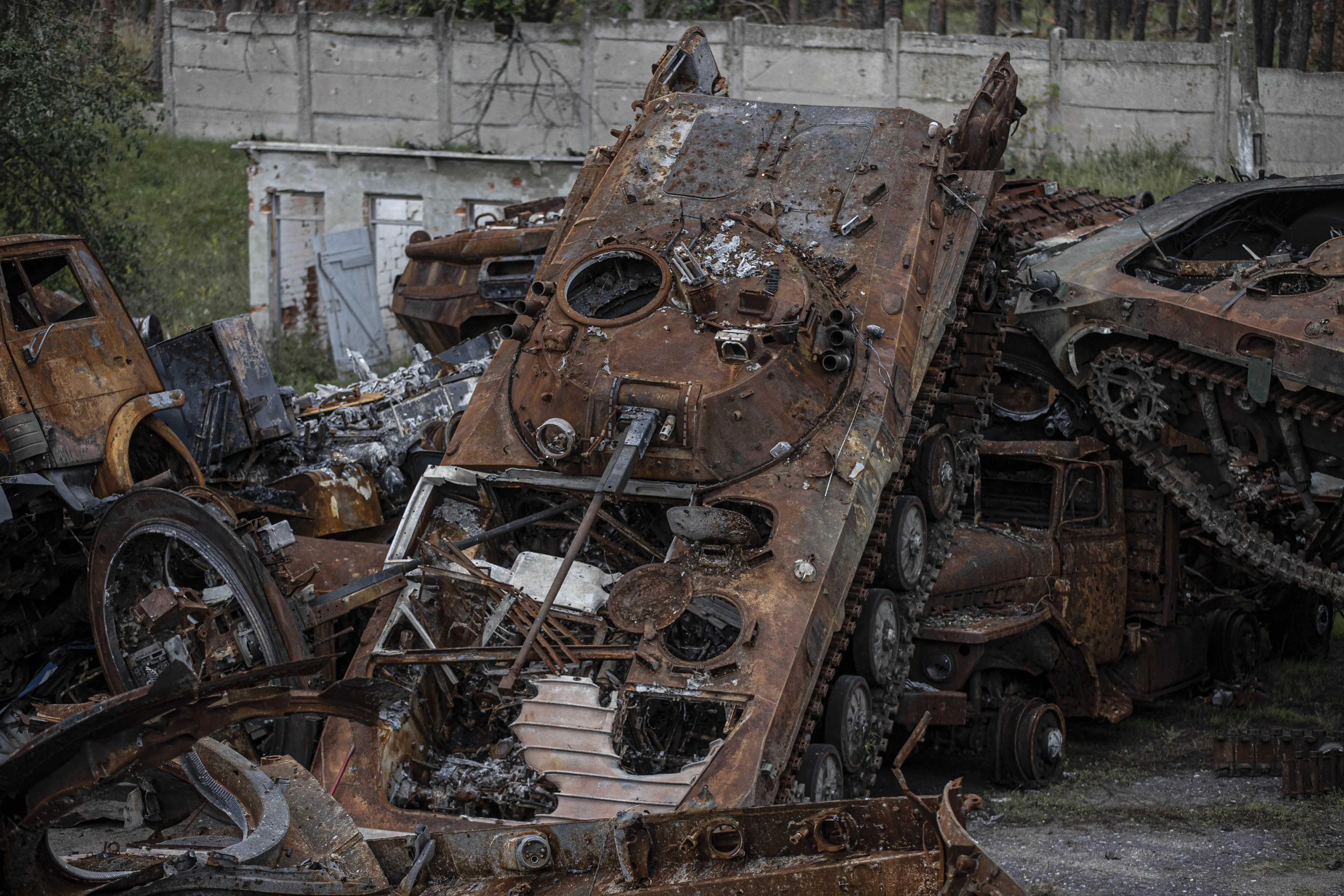 A rusted and decaying tank balancing on a pile of other rusted metal