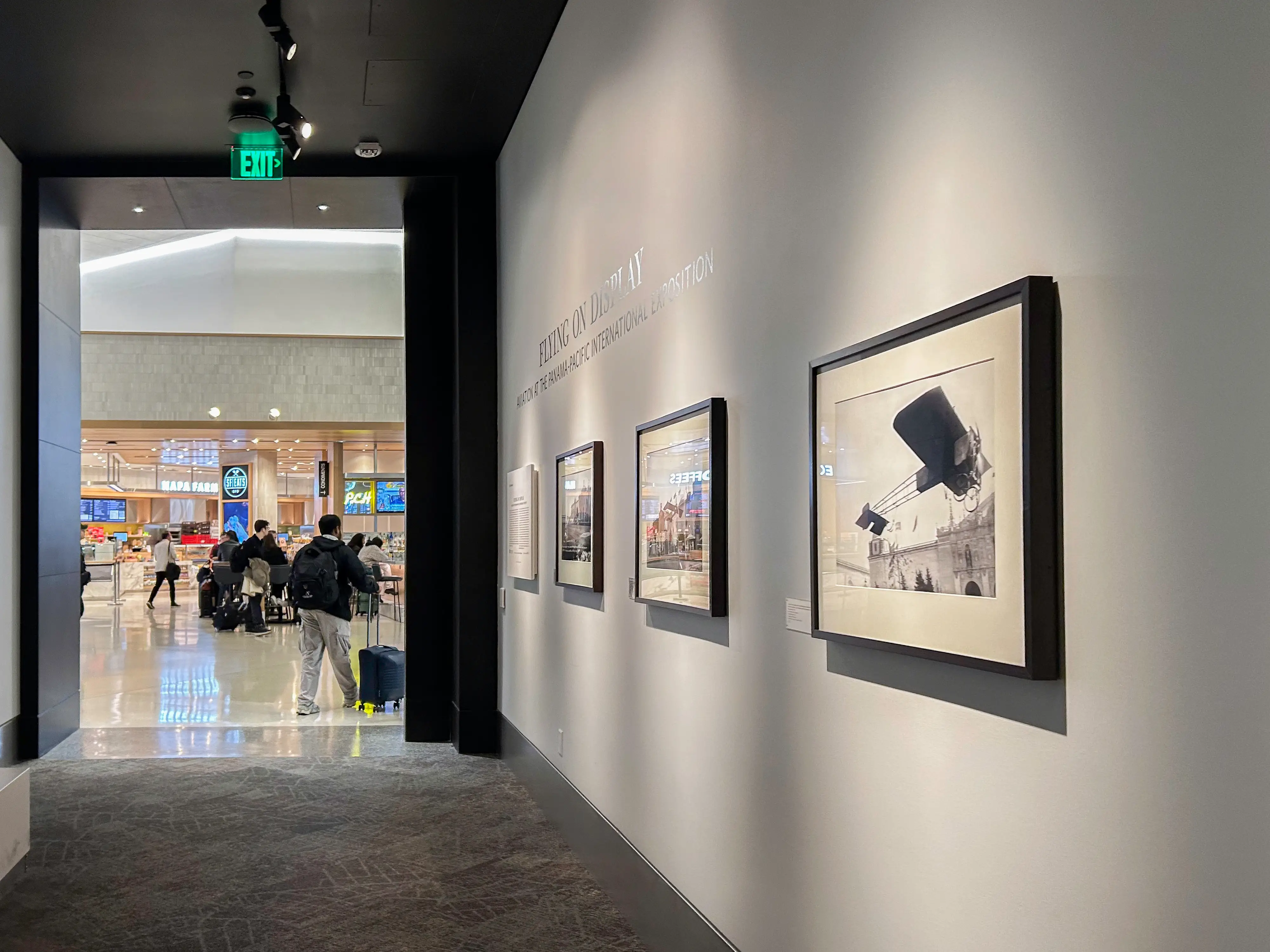 Inside an SFO terminal, there's a display of photos on the right and an opening to the rest of the terminal on the left