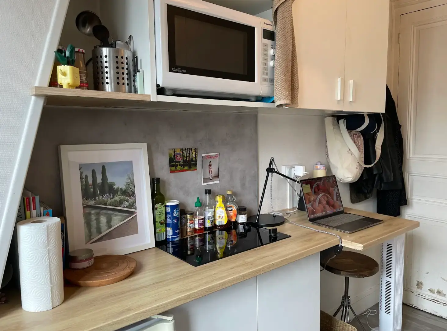 The writer's kitchen space in her micro-apartment, featuring a laptop and stool and stovetop and microwave.