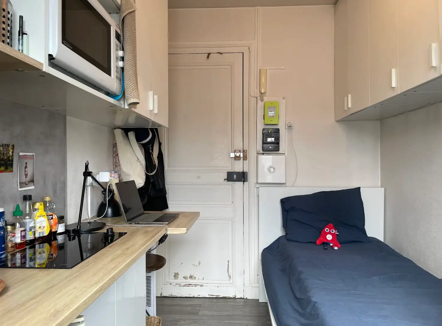 The writer's micro-apartment, including a twin bed, kitchen space, and overhead storage.