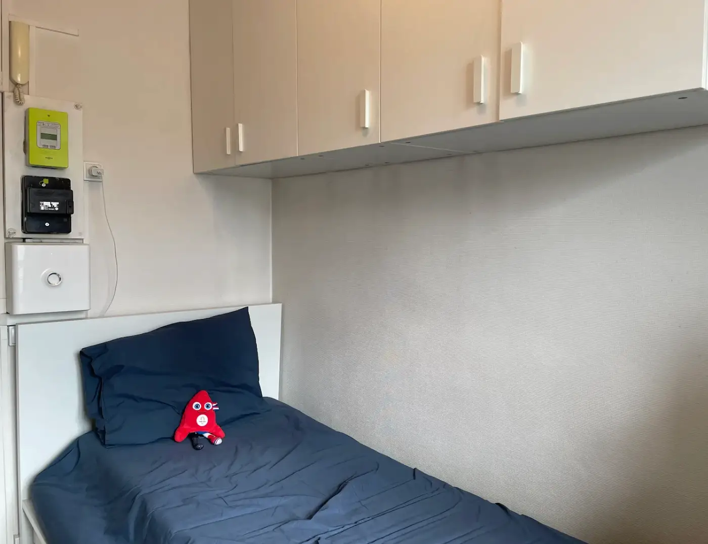 A shot of the writer's twin-sized bed with overhead cabinets.