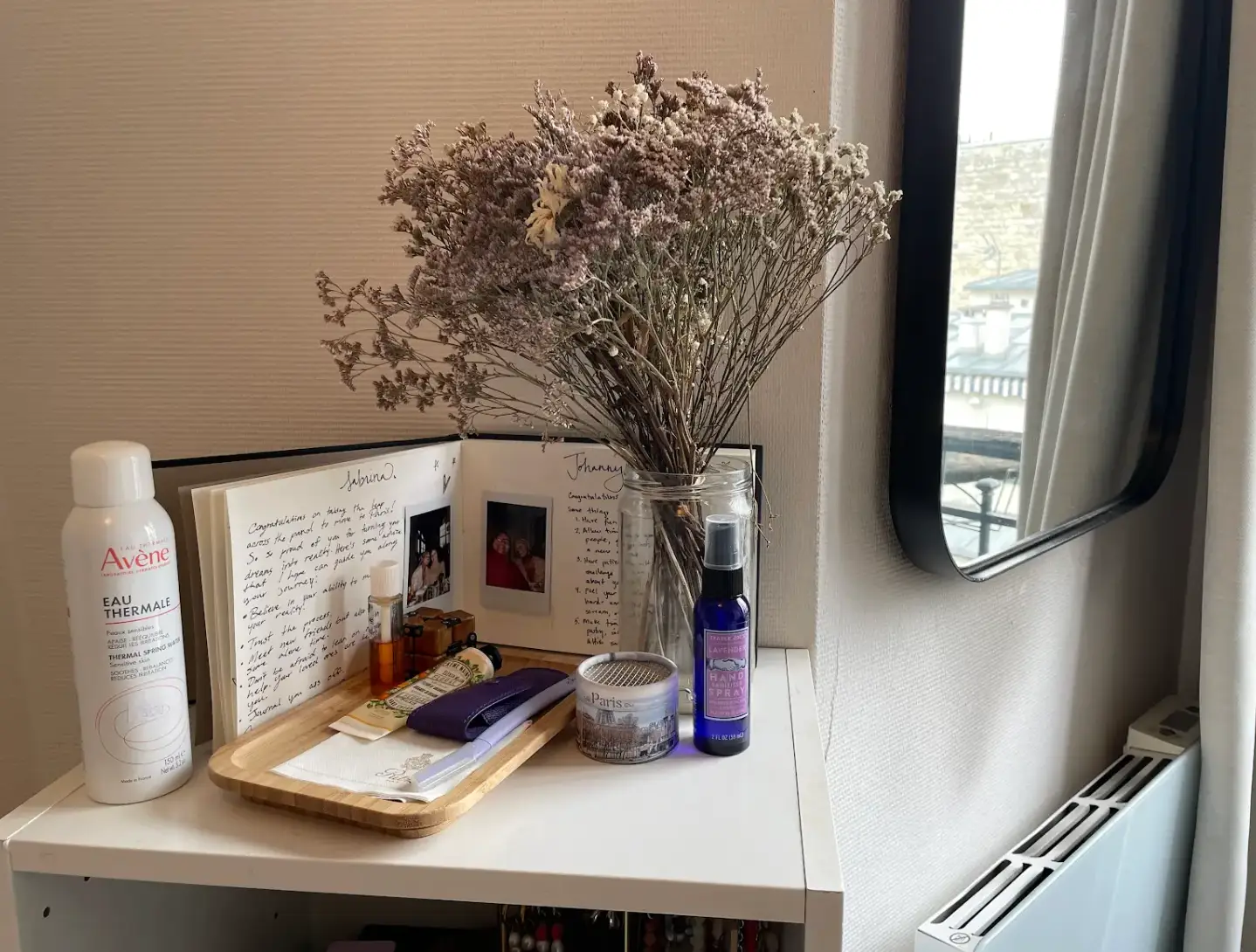 A corner of the writer's micro-apartment, featuring some lotions, hand sanitizer, a bouquet of flowers, and a scrapbook.