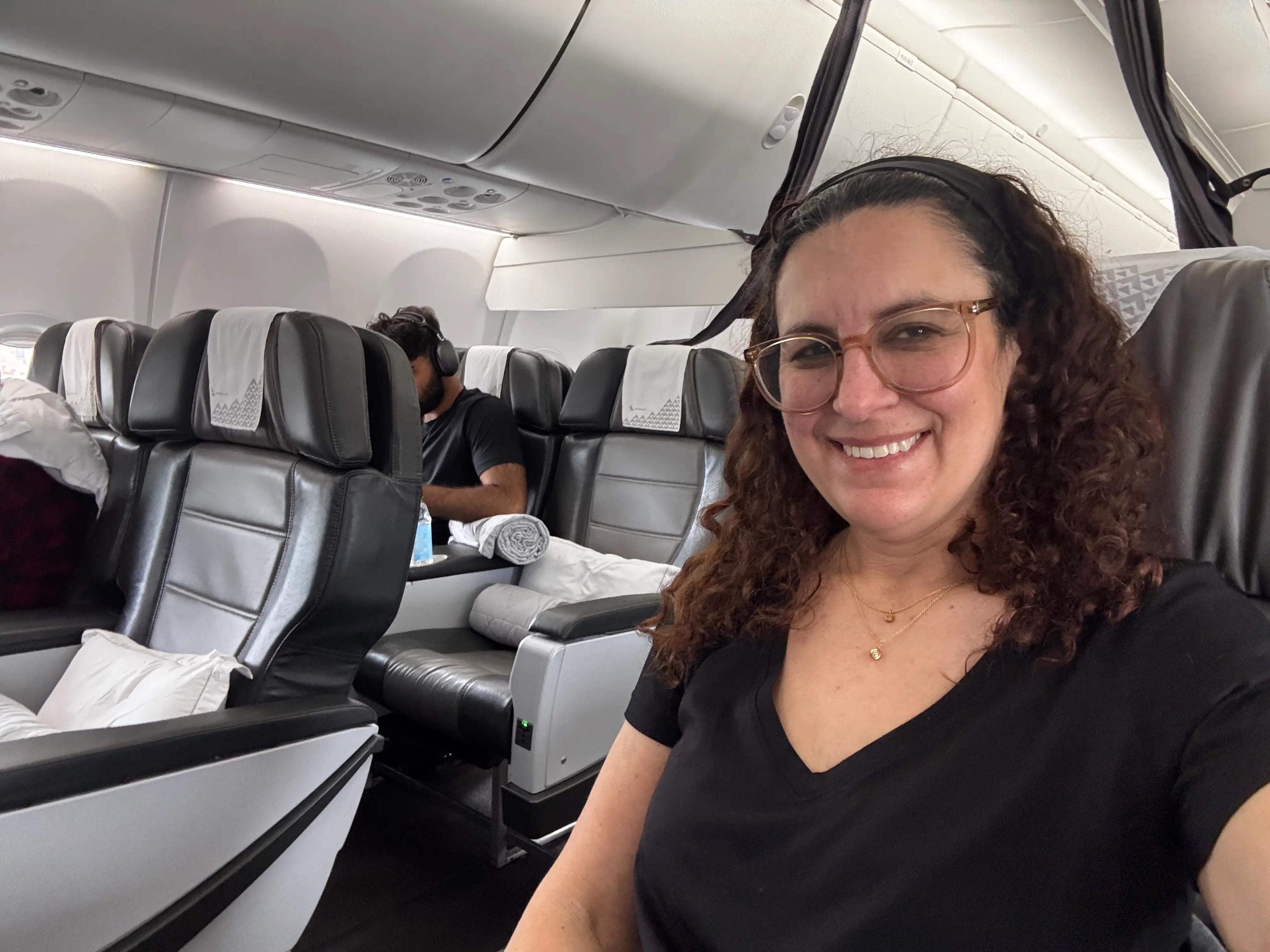 Author Jamie Davis Smith smiling on IcelandAir plane with view of Saga Premium behind her