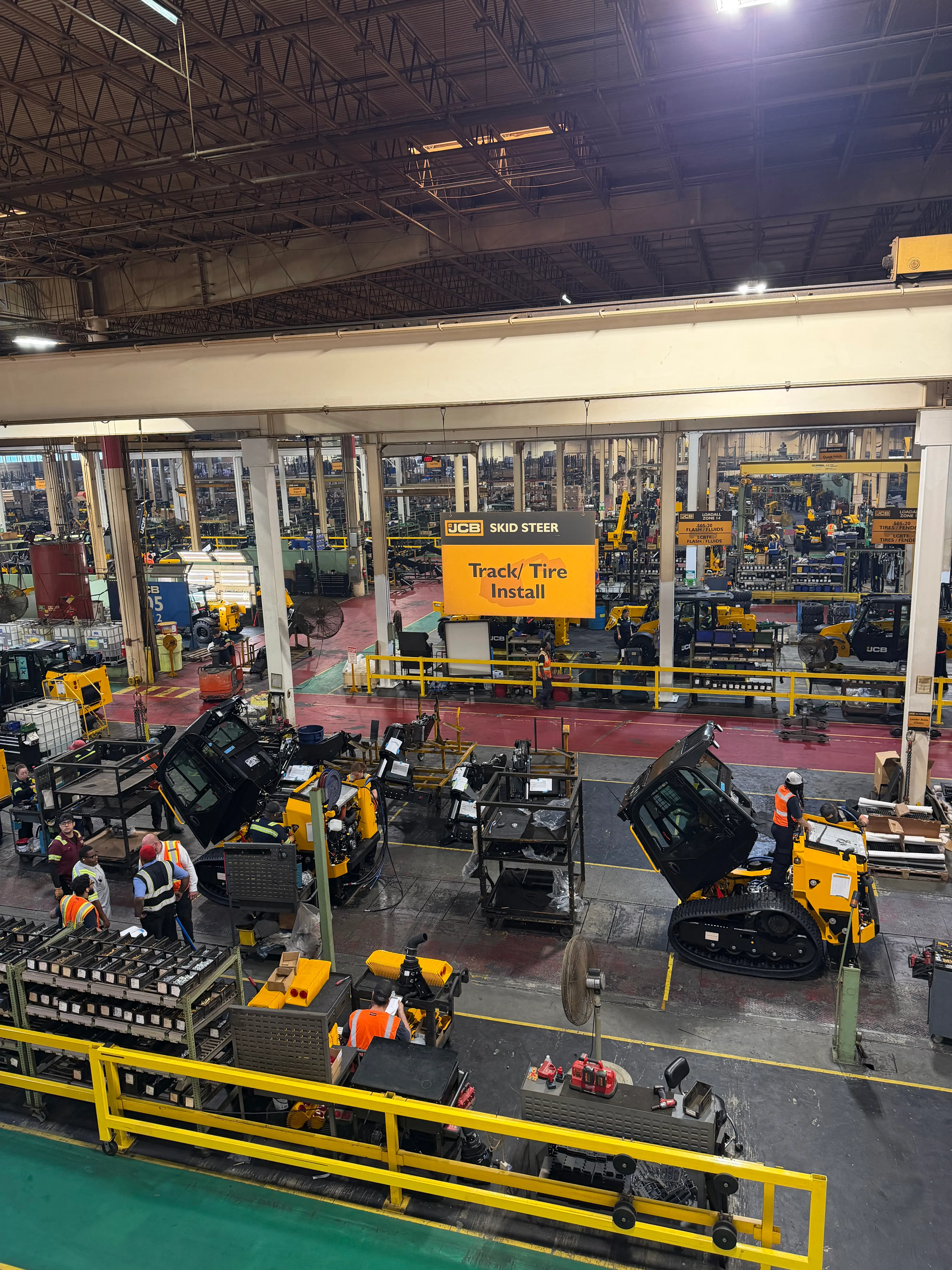 Workers assemble JCB machines on a factory production line