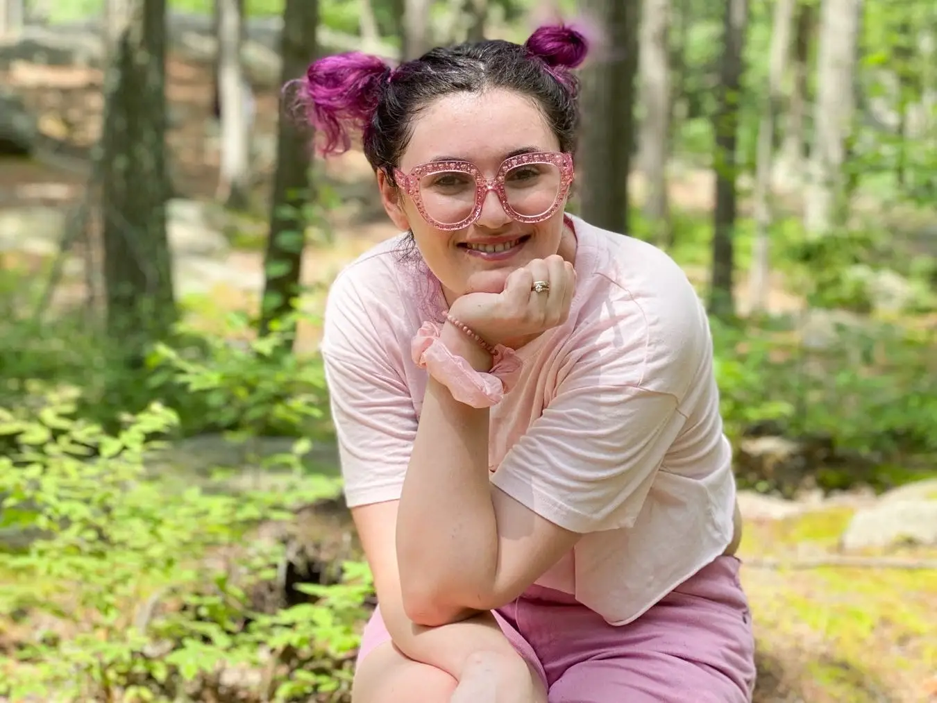 Rachel sits on a rock in the woods.