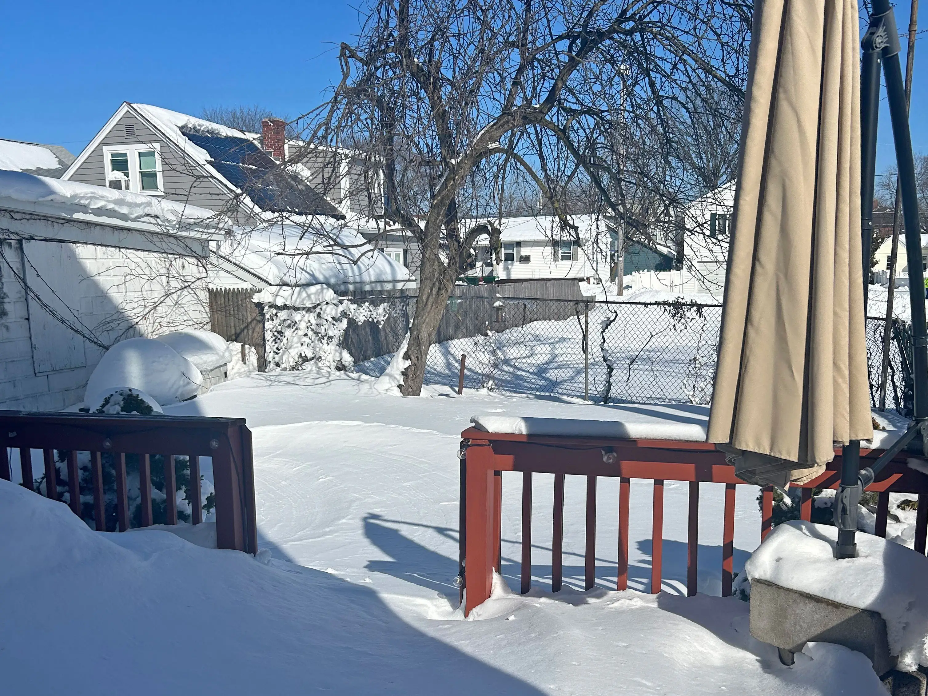 A snow-covered deck and backyard.