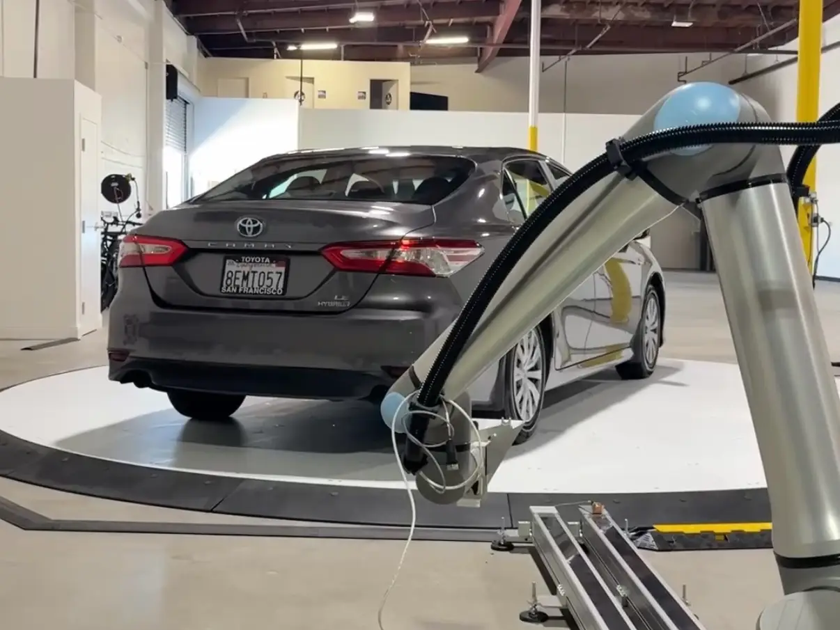 A Toyota getting scanned by a camera attached to a robot arm.