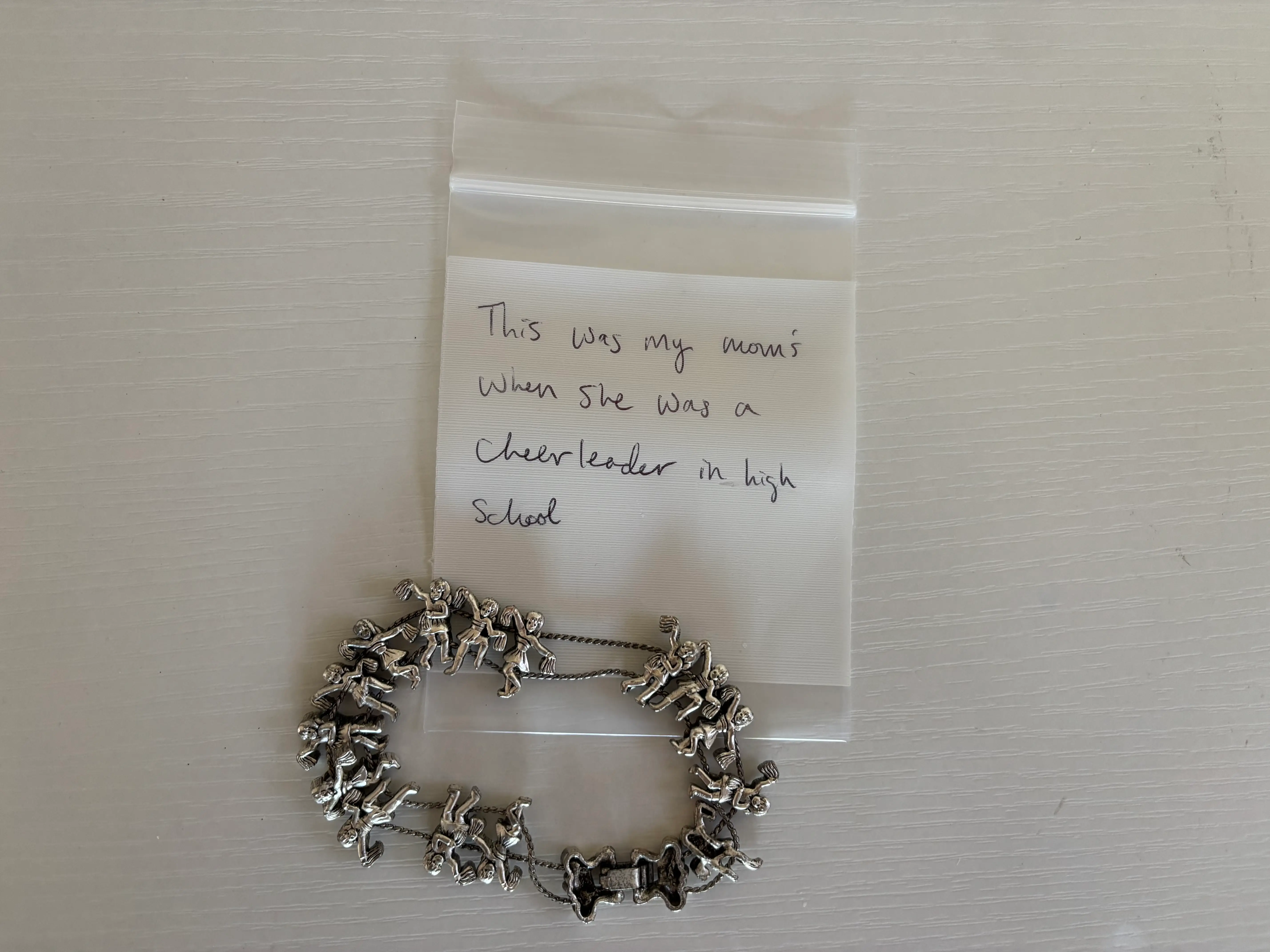 A charm bracelet with a plastic bag, that says