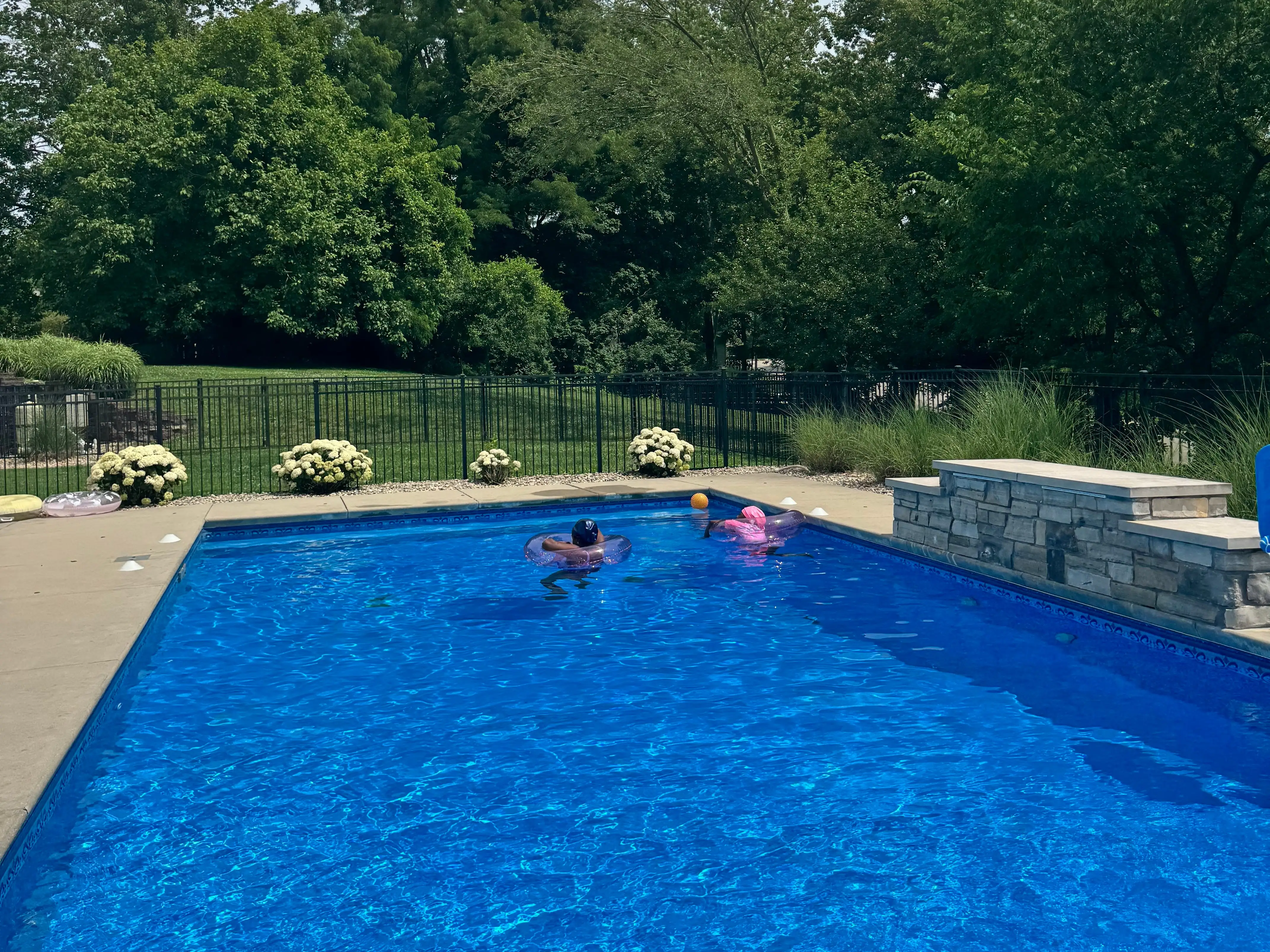 Two kids enjoying a backyard pool.