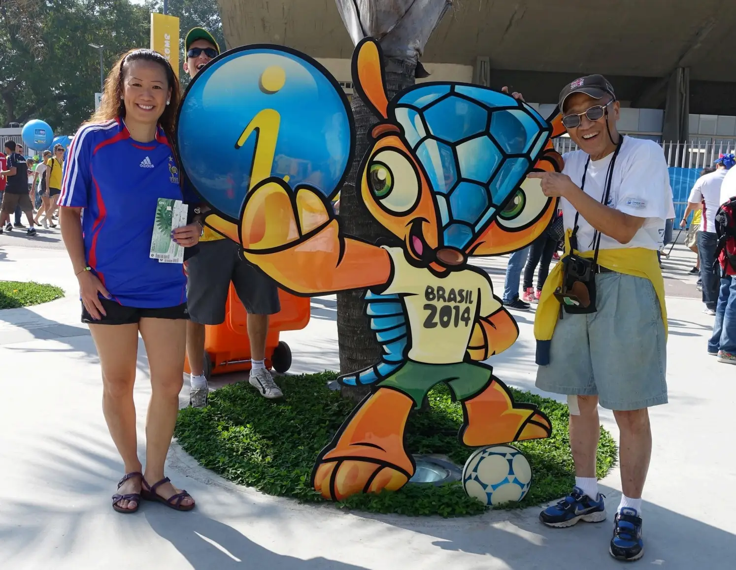 May Lee and her father pose next to the 2014 Brazil World Cup mascot.