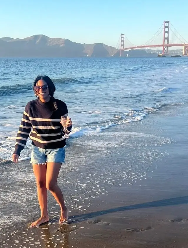 A woman at the beach with the Golden Gate Bridge in the background.