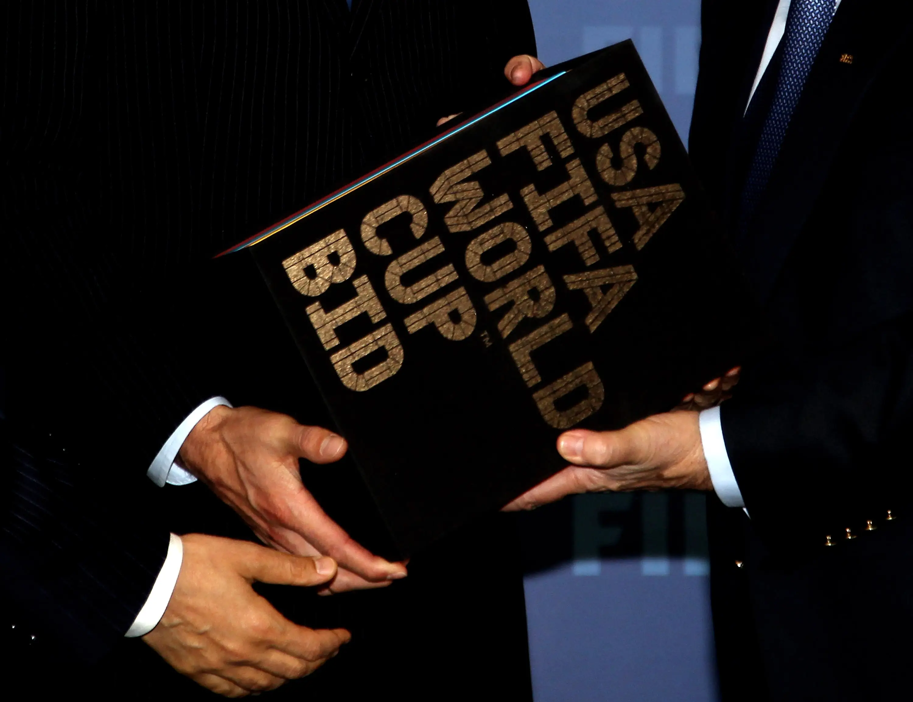 Hands hold the US bid book for the World Cup presented to FIFA in 2010.