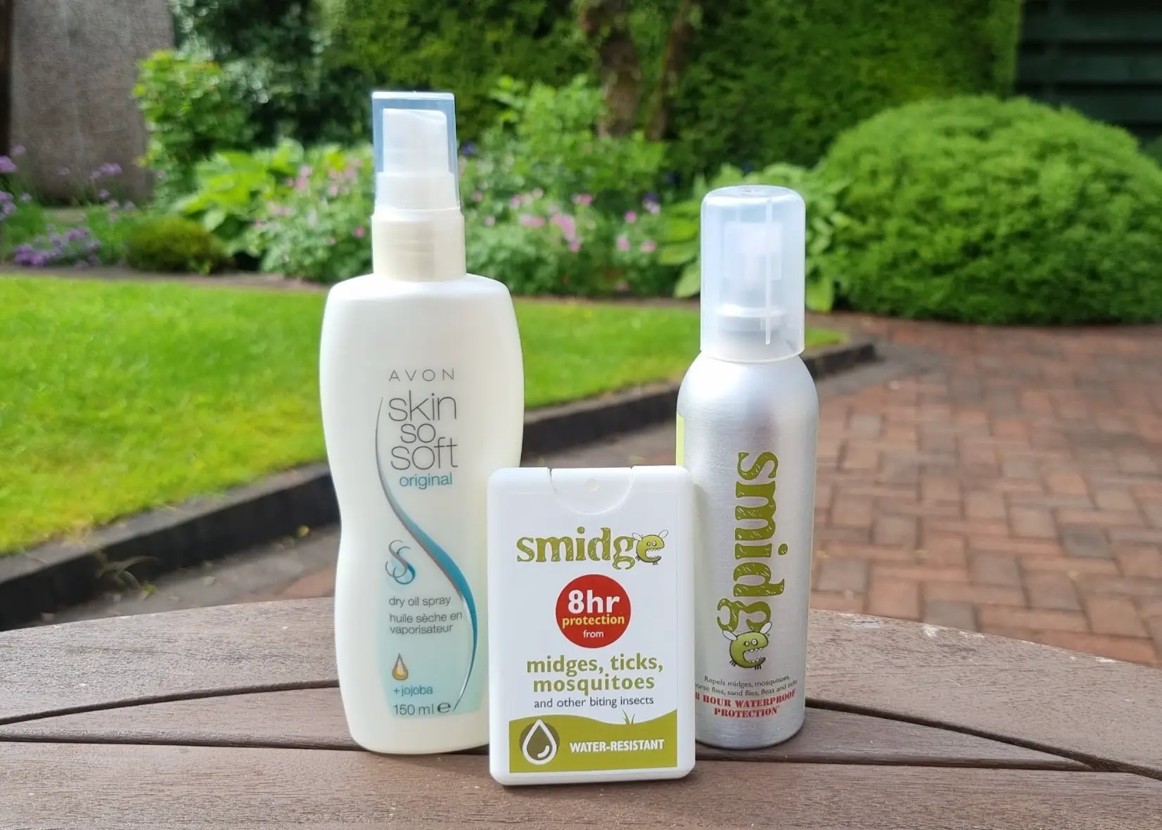 Three bottles of bug spray on a brown table outside.