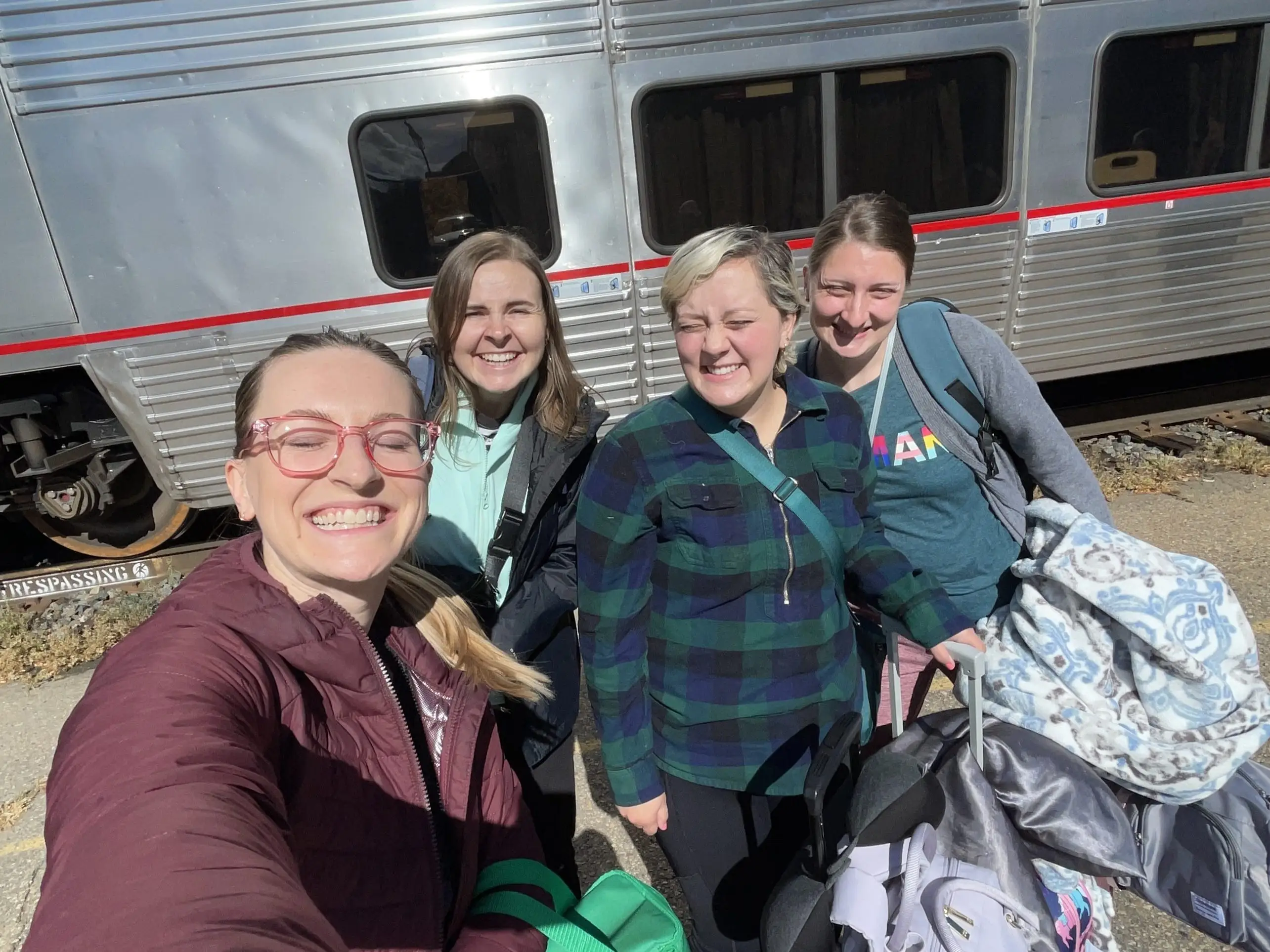 Four friends posing in front of an Amtrak train in Glenwood Springs, Colorado.