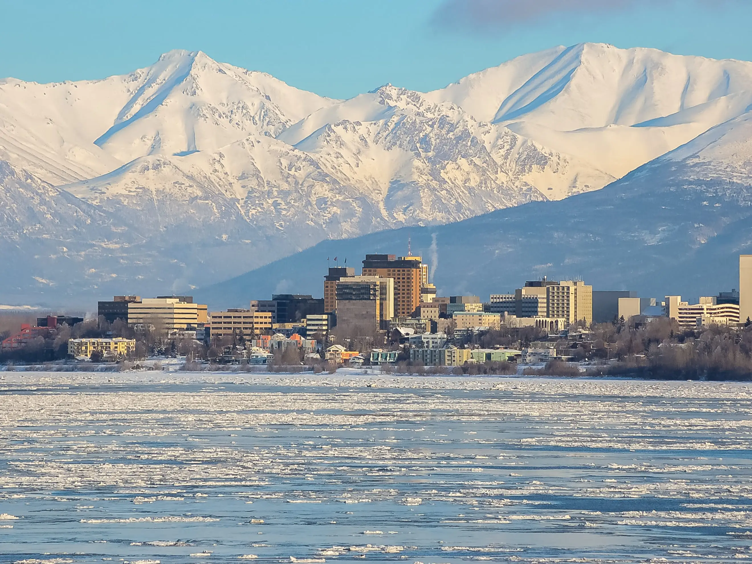 Downtown Anchorage, Alaska on the water with mountains in the background.