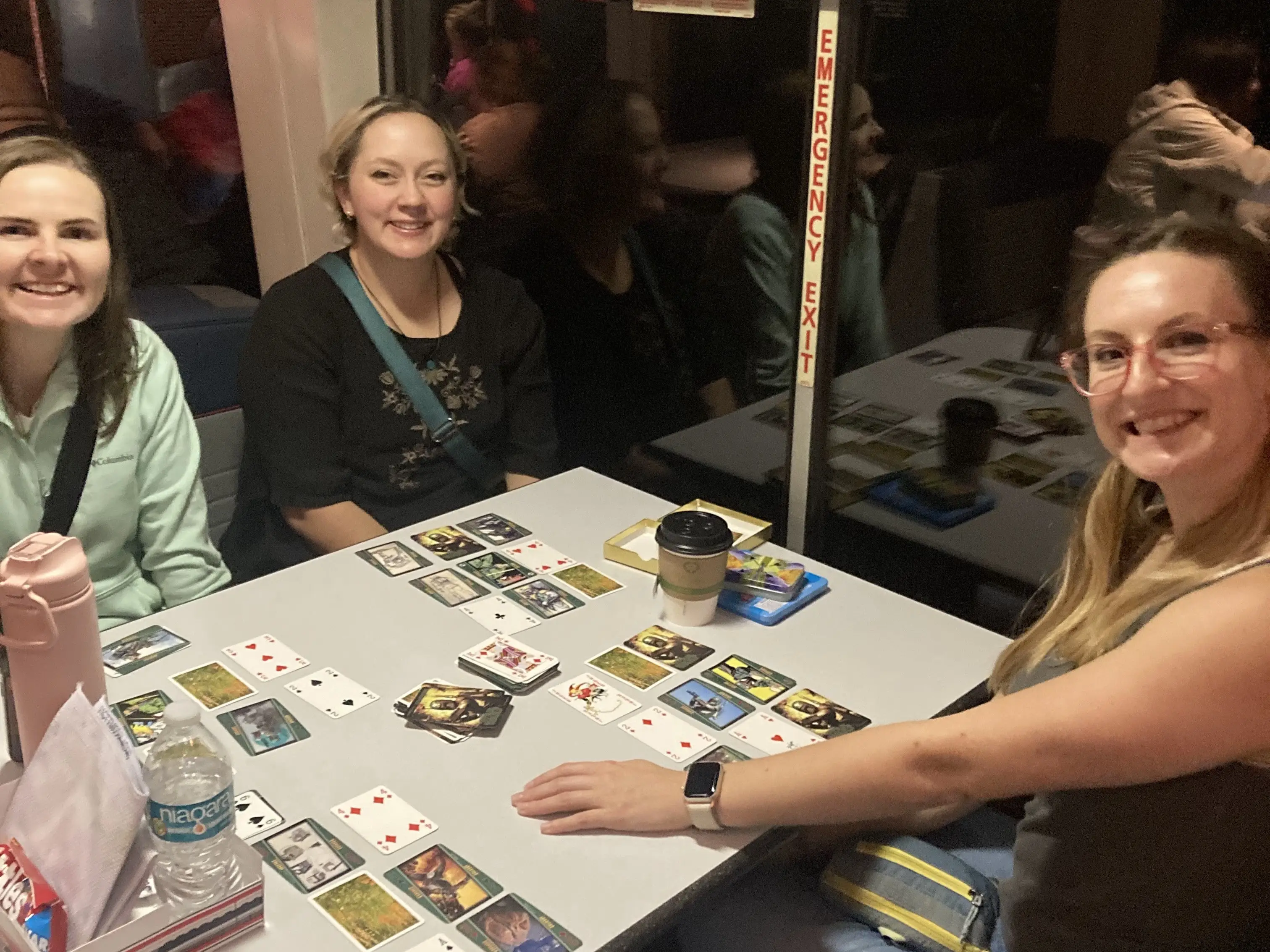 A group of friends playing card games while riding an Amtrak train.