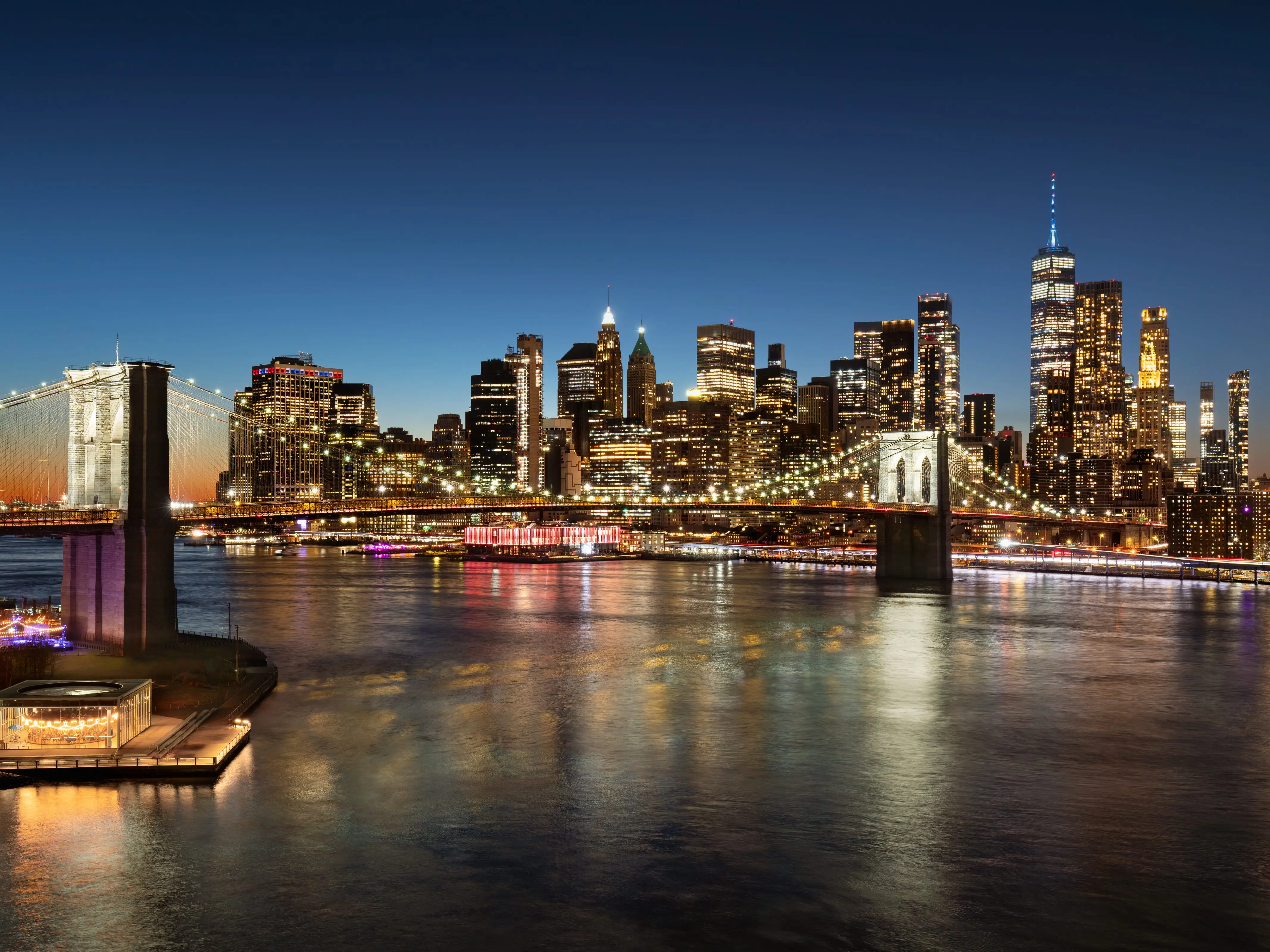 Elevated evening view of Brooklyn Bridge, Lower Manhattan skyscrapers, and East River. Twilight cityscape with illuminated New York City skyline stock photo