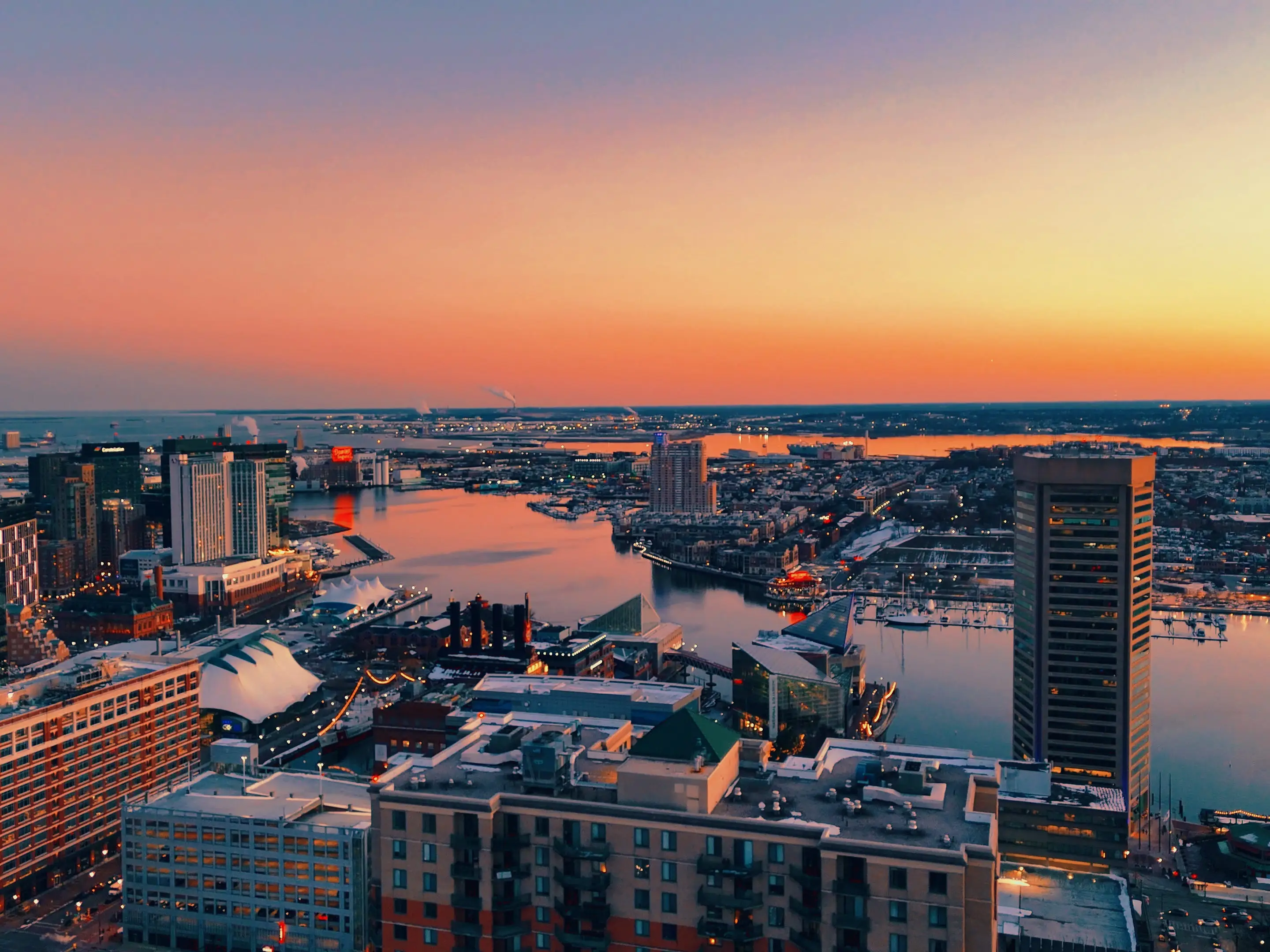 Progression over the City of Baltimore toward the inner harbor while hopping over each building that's constructed below as the focus bounces across the skyline and into the rich colors of the horizon