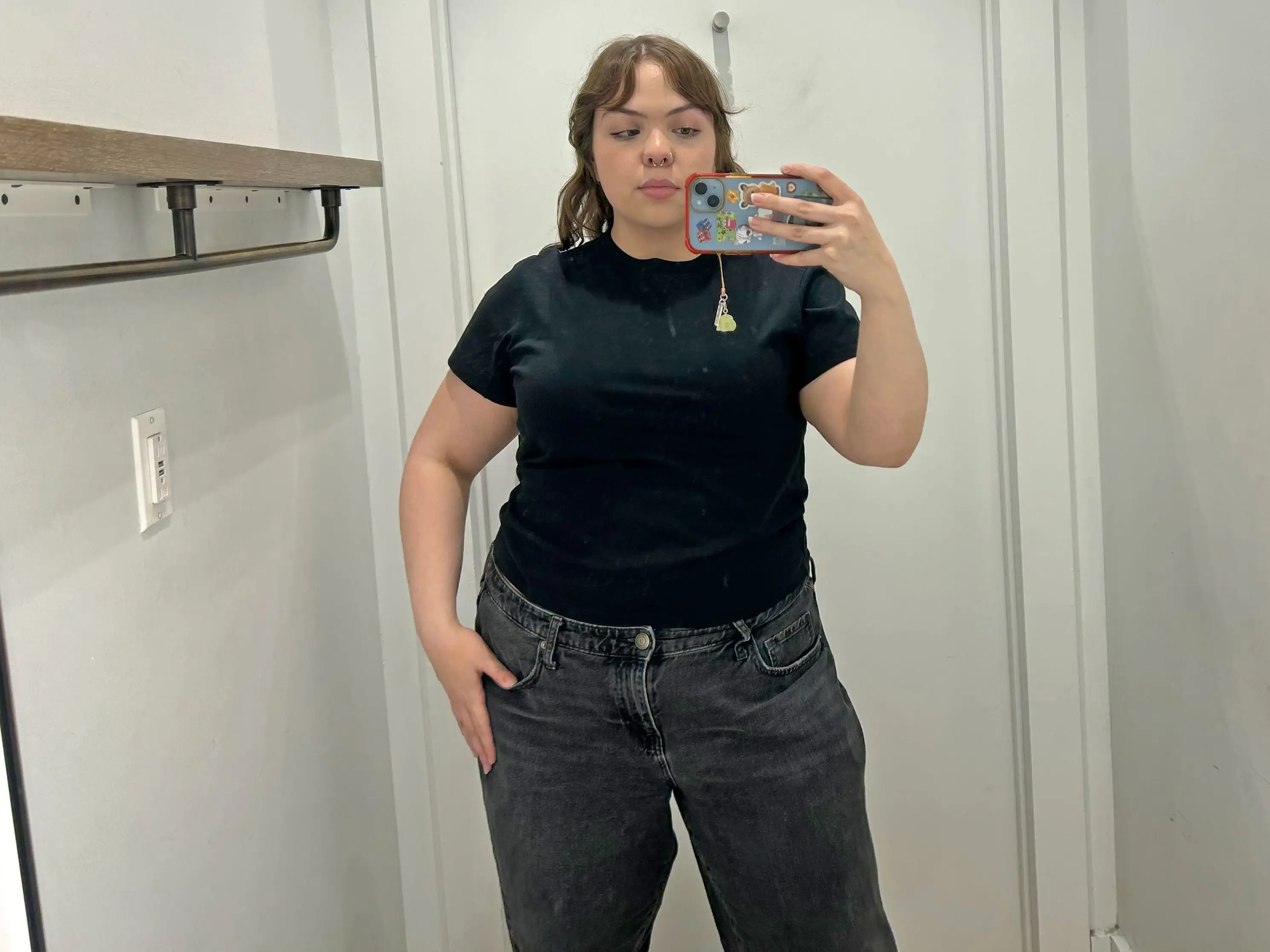Amena wearing a black crewneck T-shirt in a fitting room.