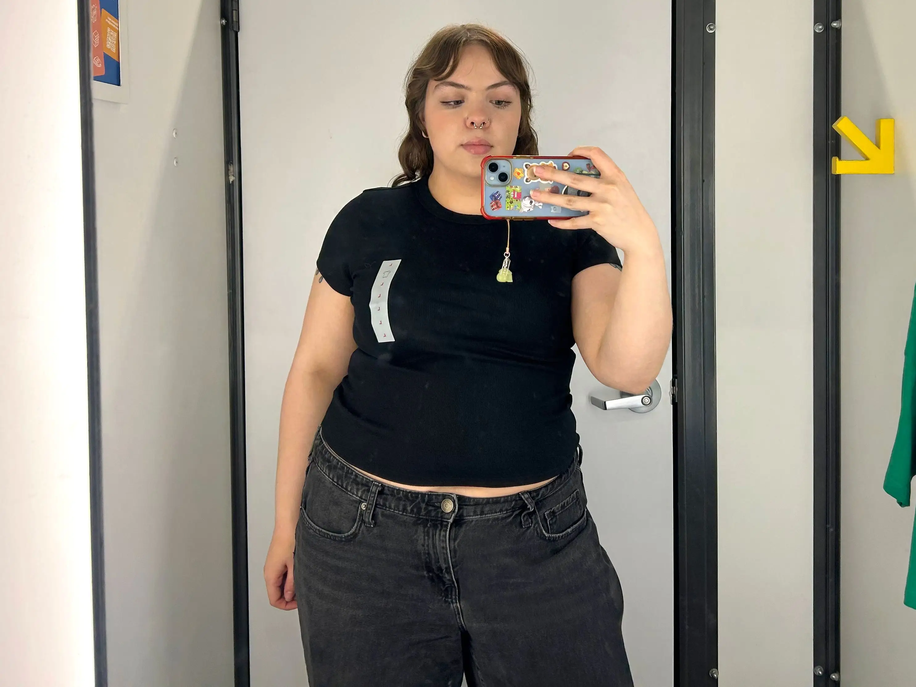 Amena wearing a black crewneck T-shirt in a fitting room.