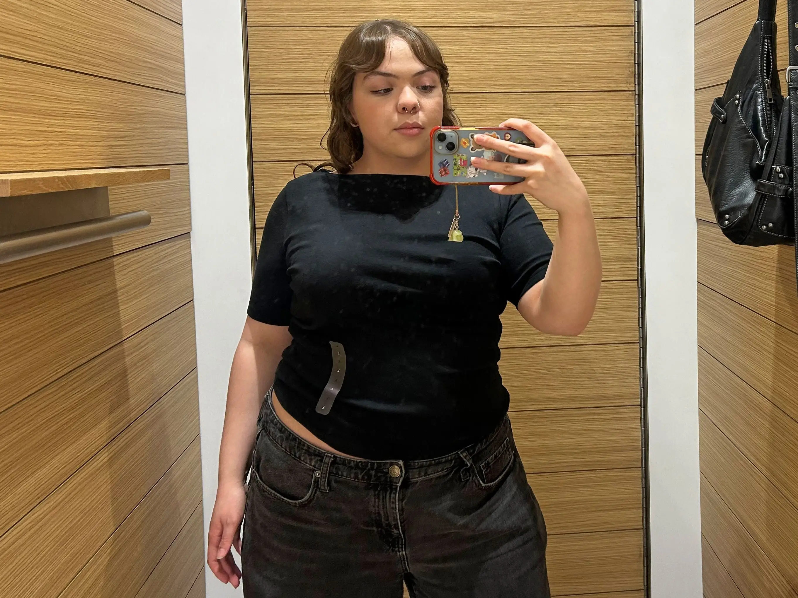 Amena wearing a black boatneck T-shirt in a fitting room.