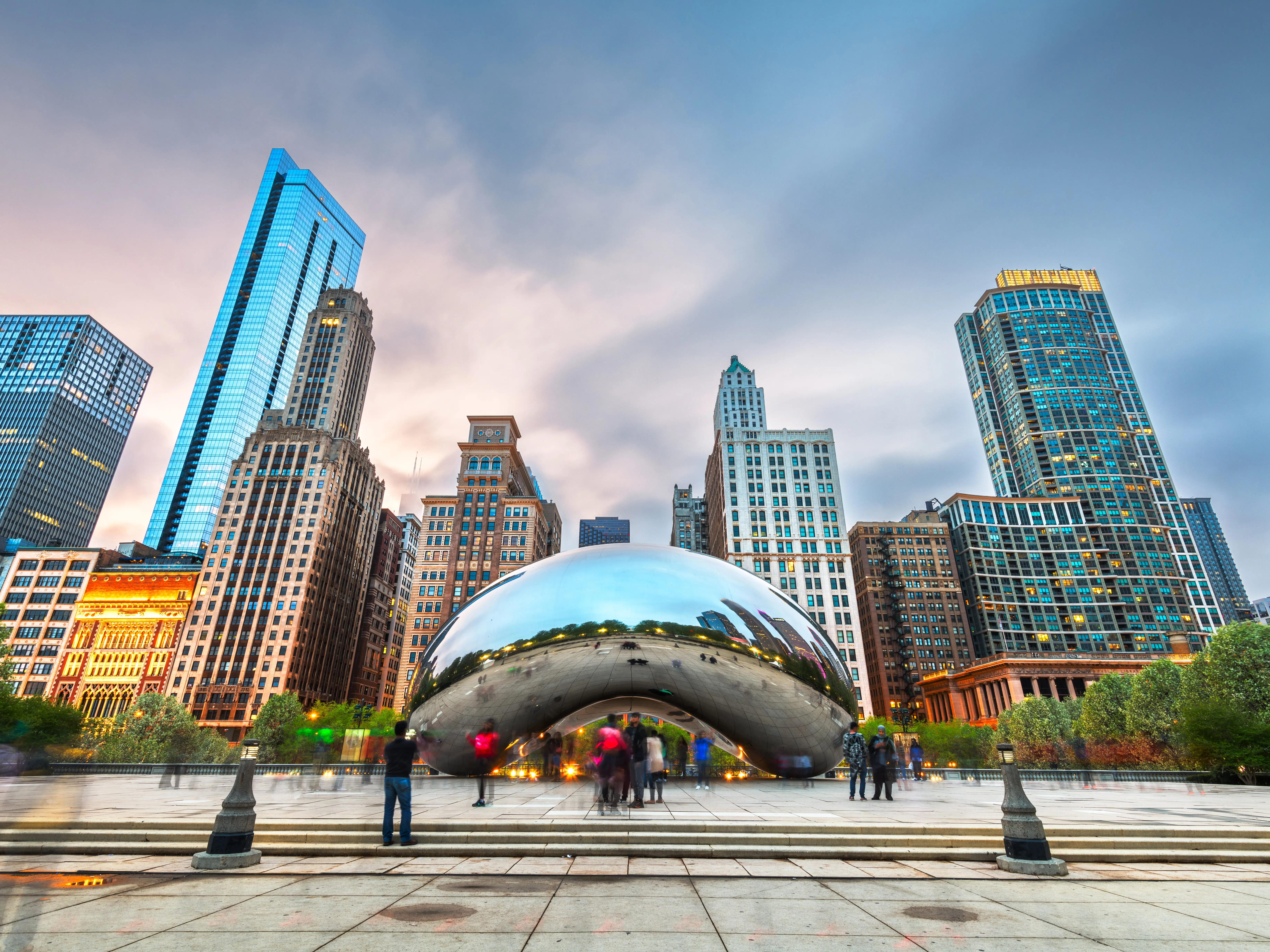 Chicago, IL, USA - May 12, 2018: Tourists visit Cloud Gate in Millennium Park in the evening. The sculpture was completed in 2006.
