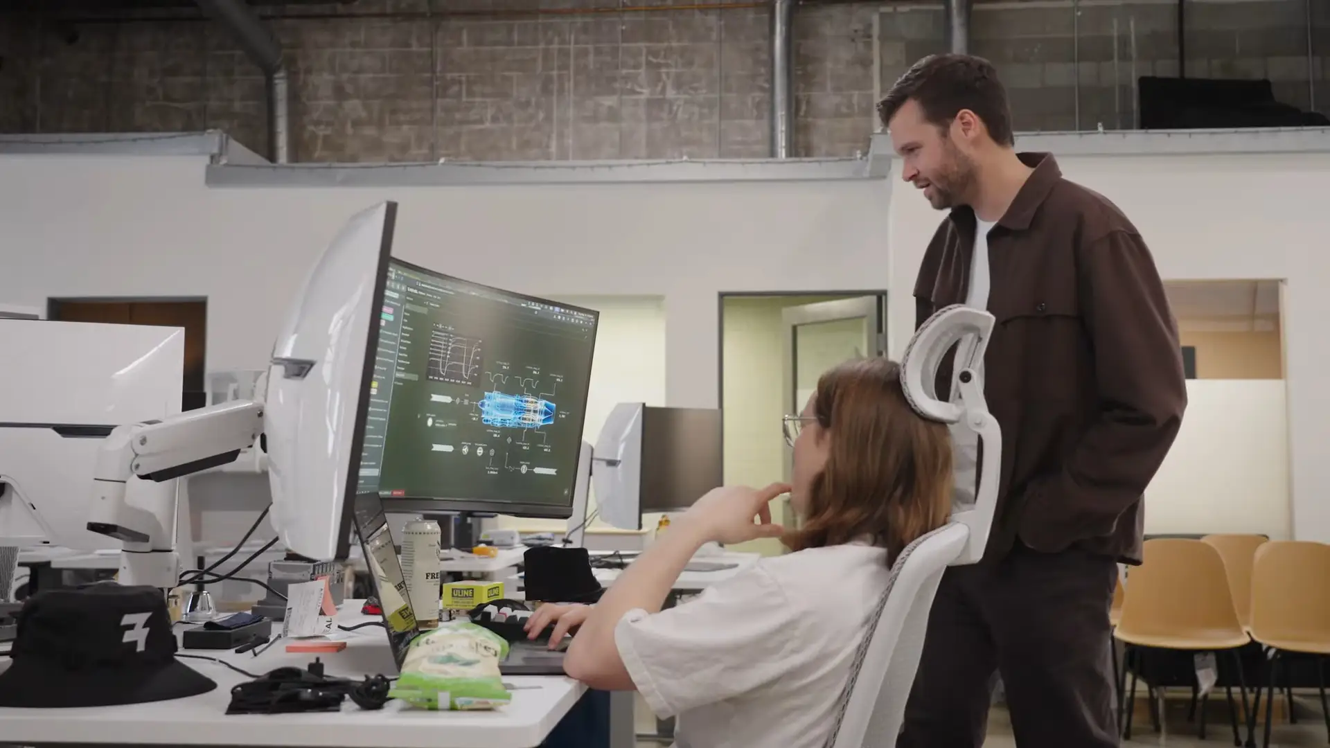 Scott Morton, CEO of Revel, stands in a brown jacket while looking at a computer.