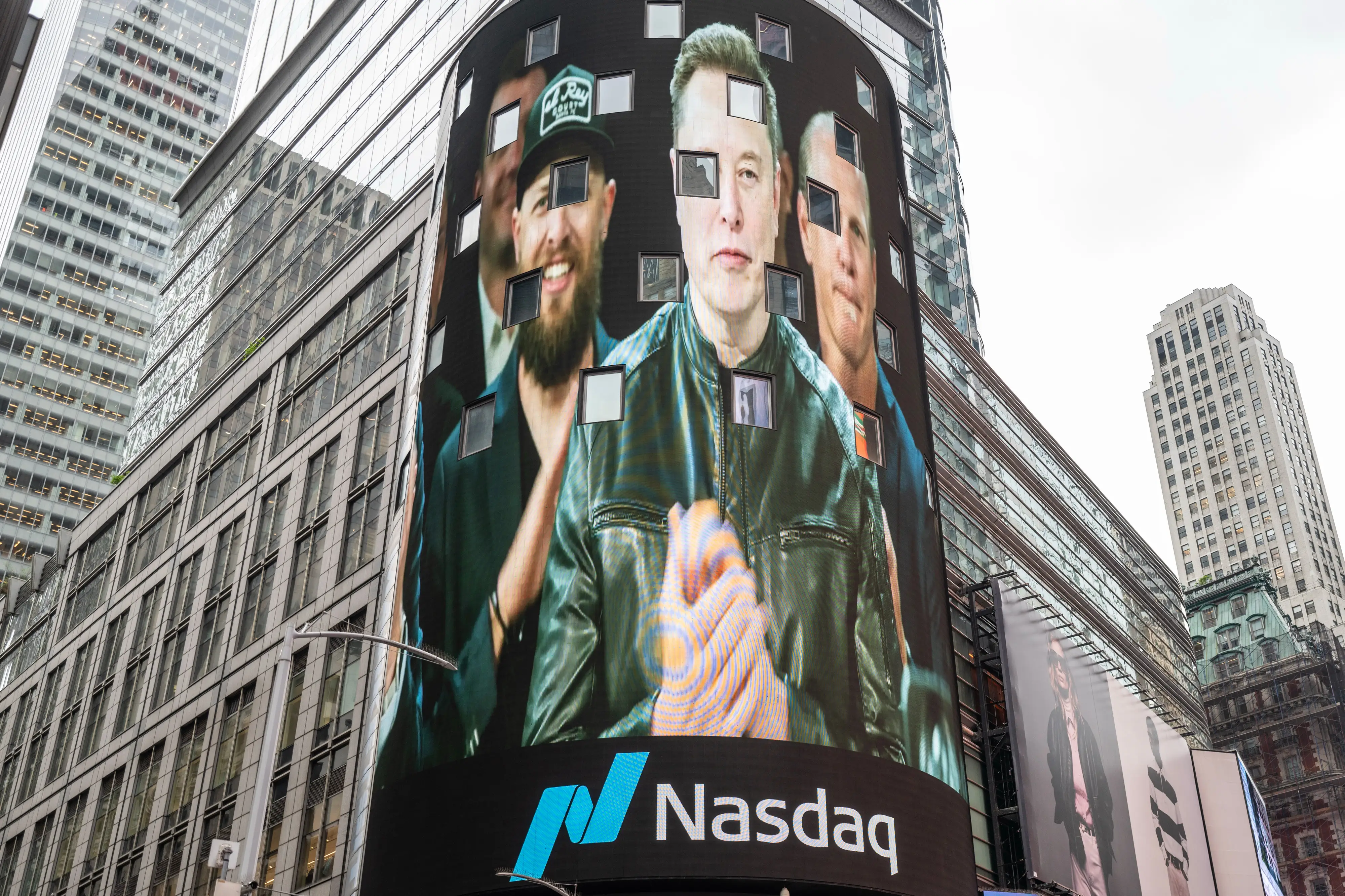 Elon Musk, wearing a leather jacket, is projected on a screen in Times Square during SpaceX's stock opening.