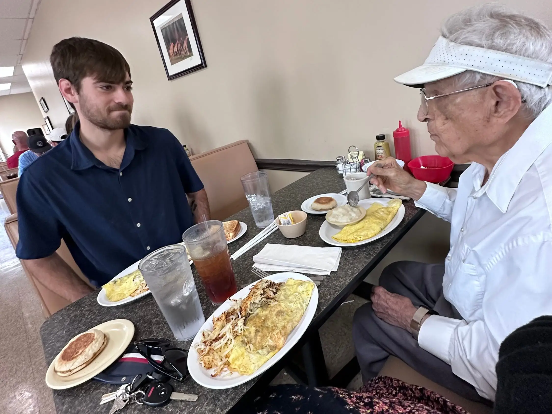 A young man having a meal with a senior