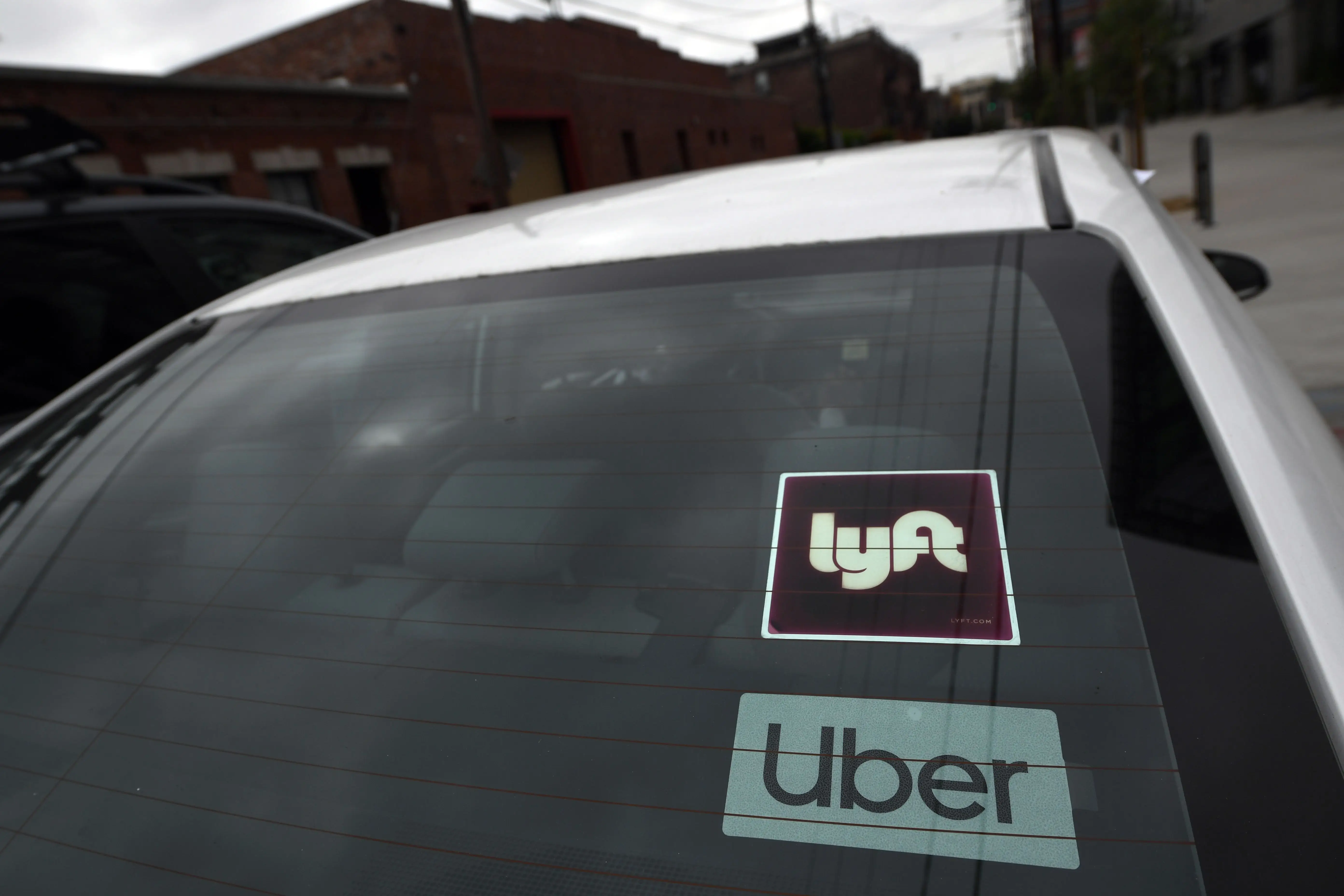 A car's back window includes stickers for Uber and Lyft.