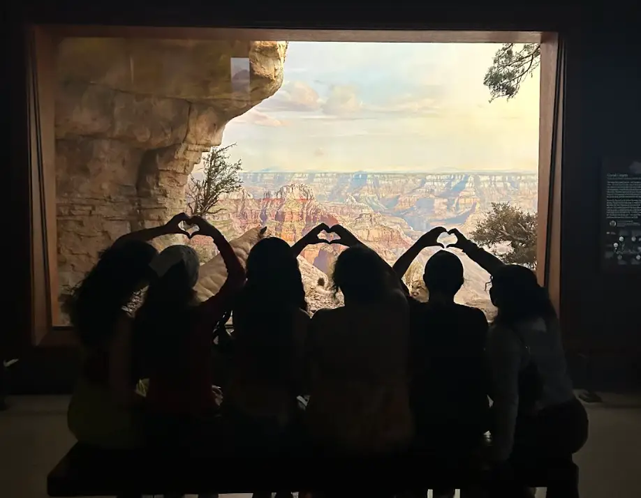 A group of the writer's friends, silhouetted in black, posing and holding up heart hands at a museum in New York City.