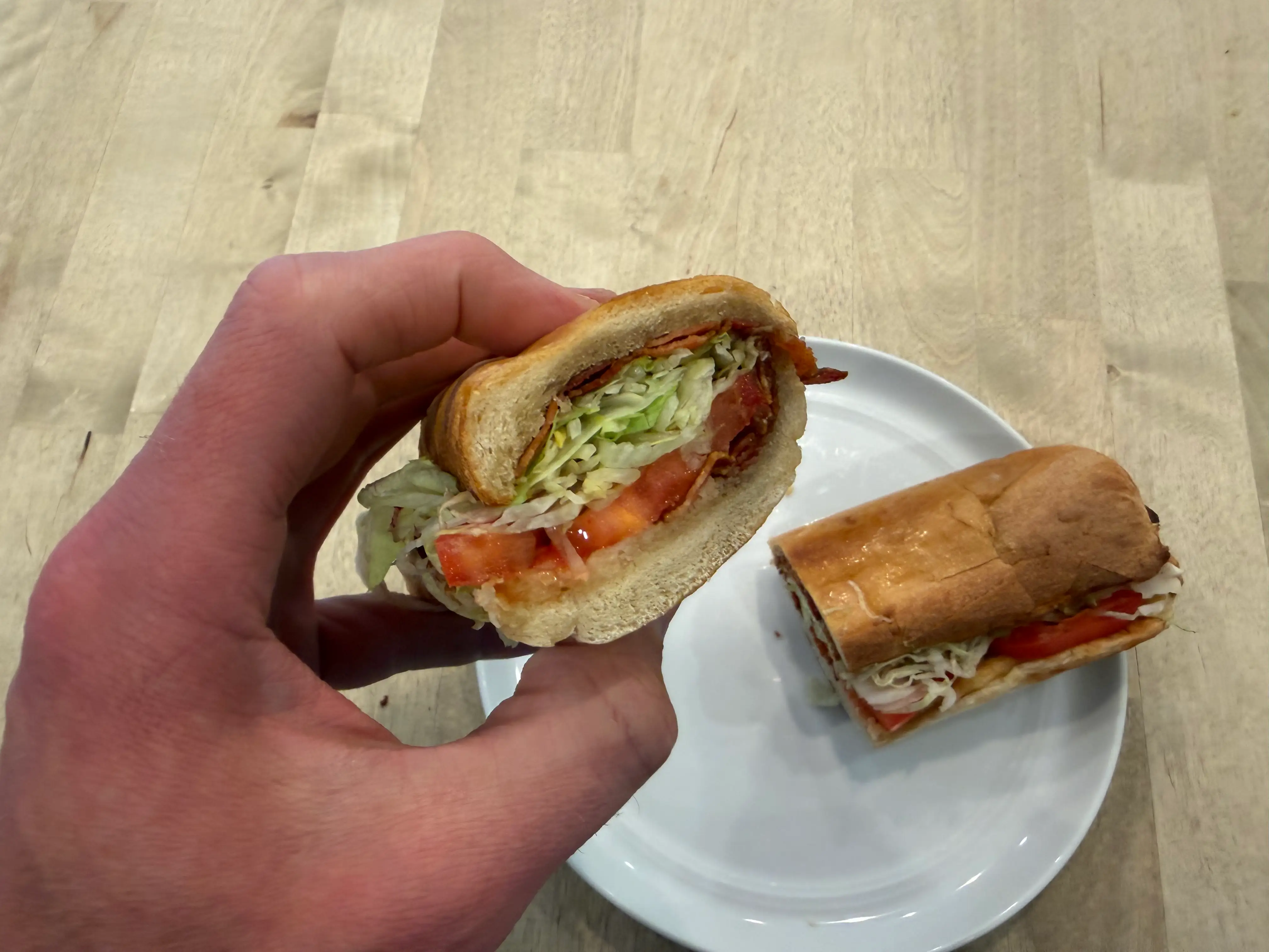 Hand holding half of BLT sandwich