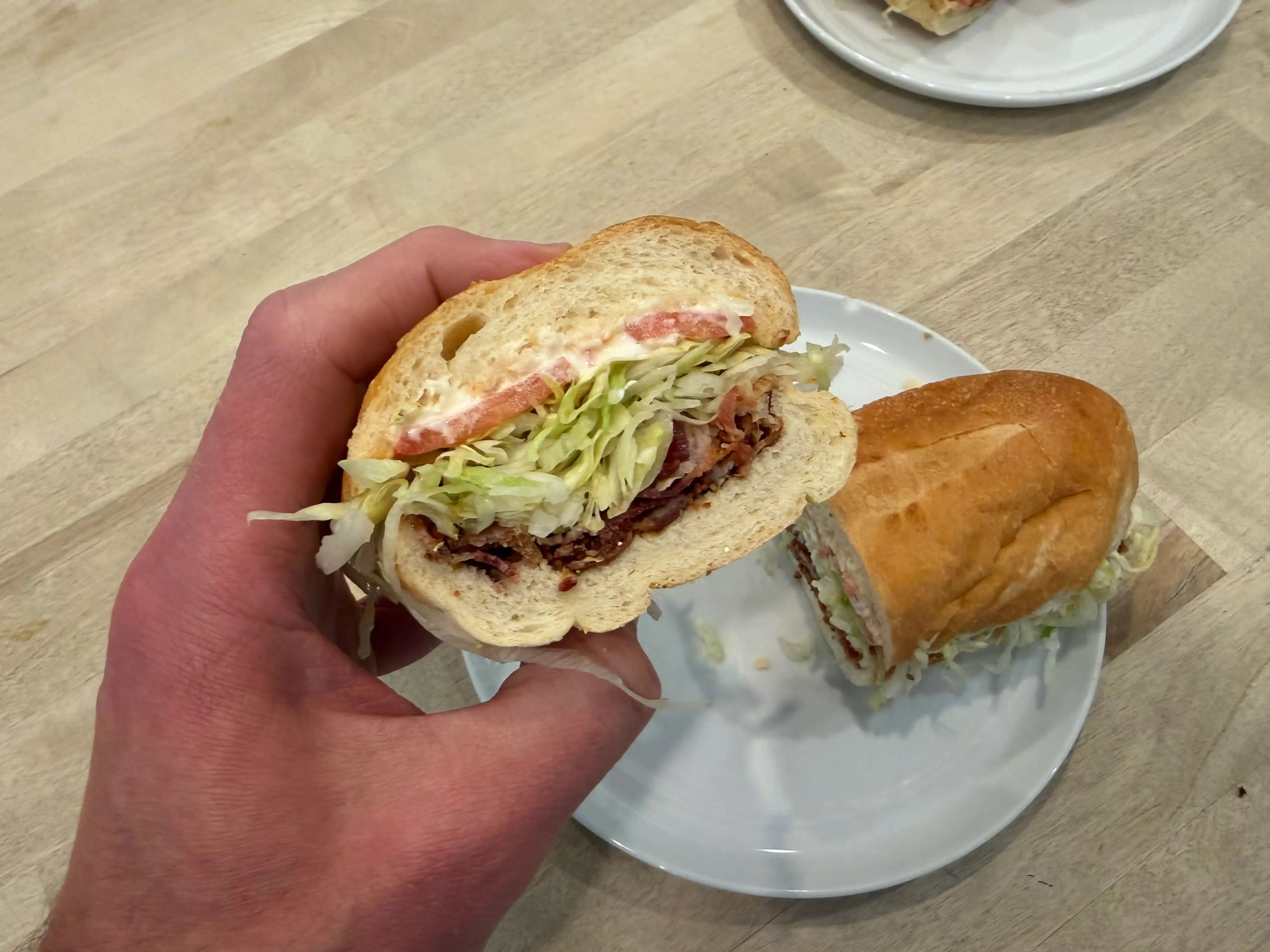 Hand holding half of BLT sandwich