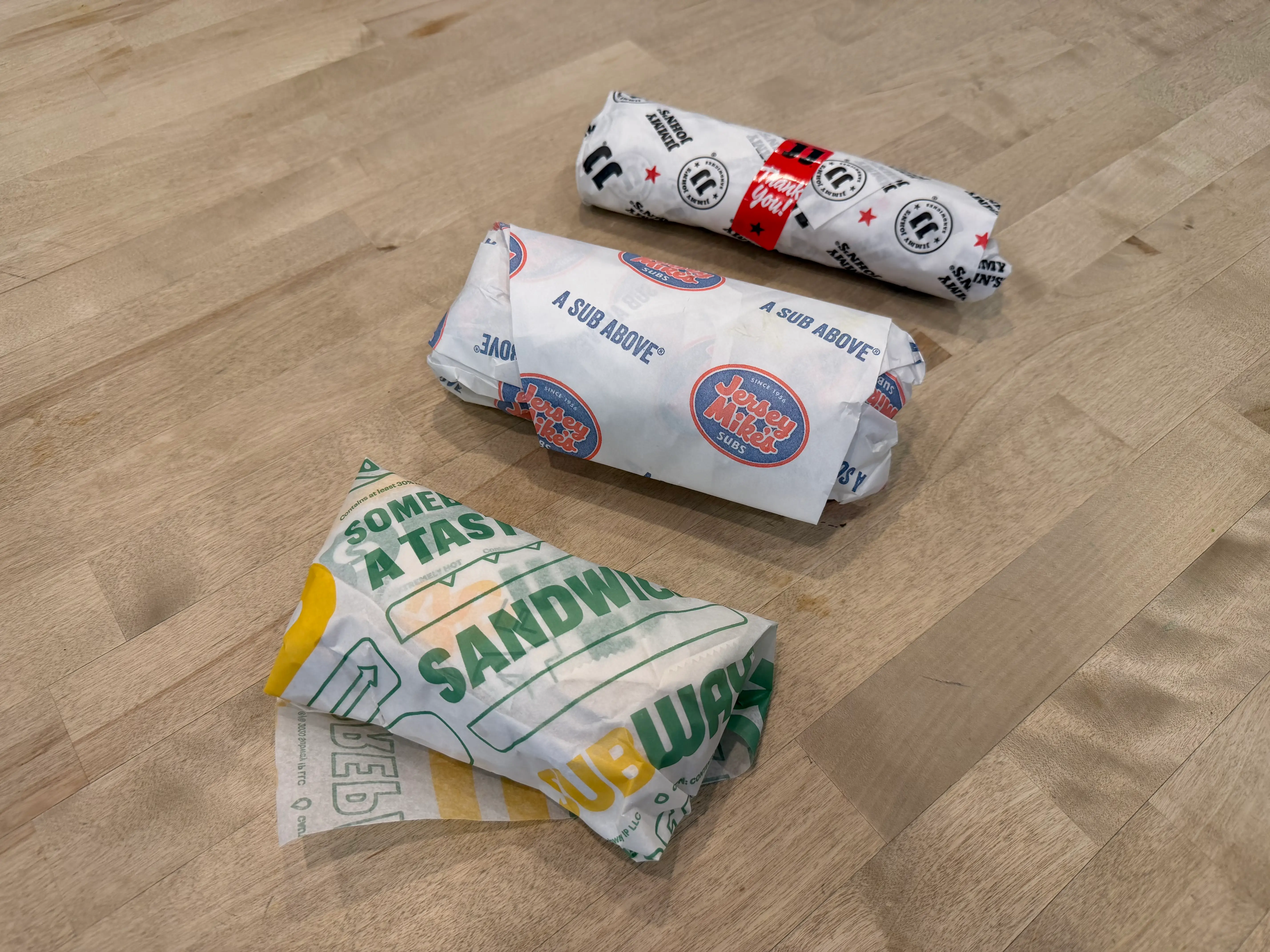 Subway, Jimmy Johns, and Jersey Mike's wrapped sandwiches on table