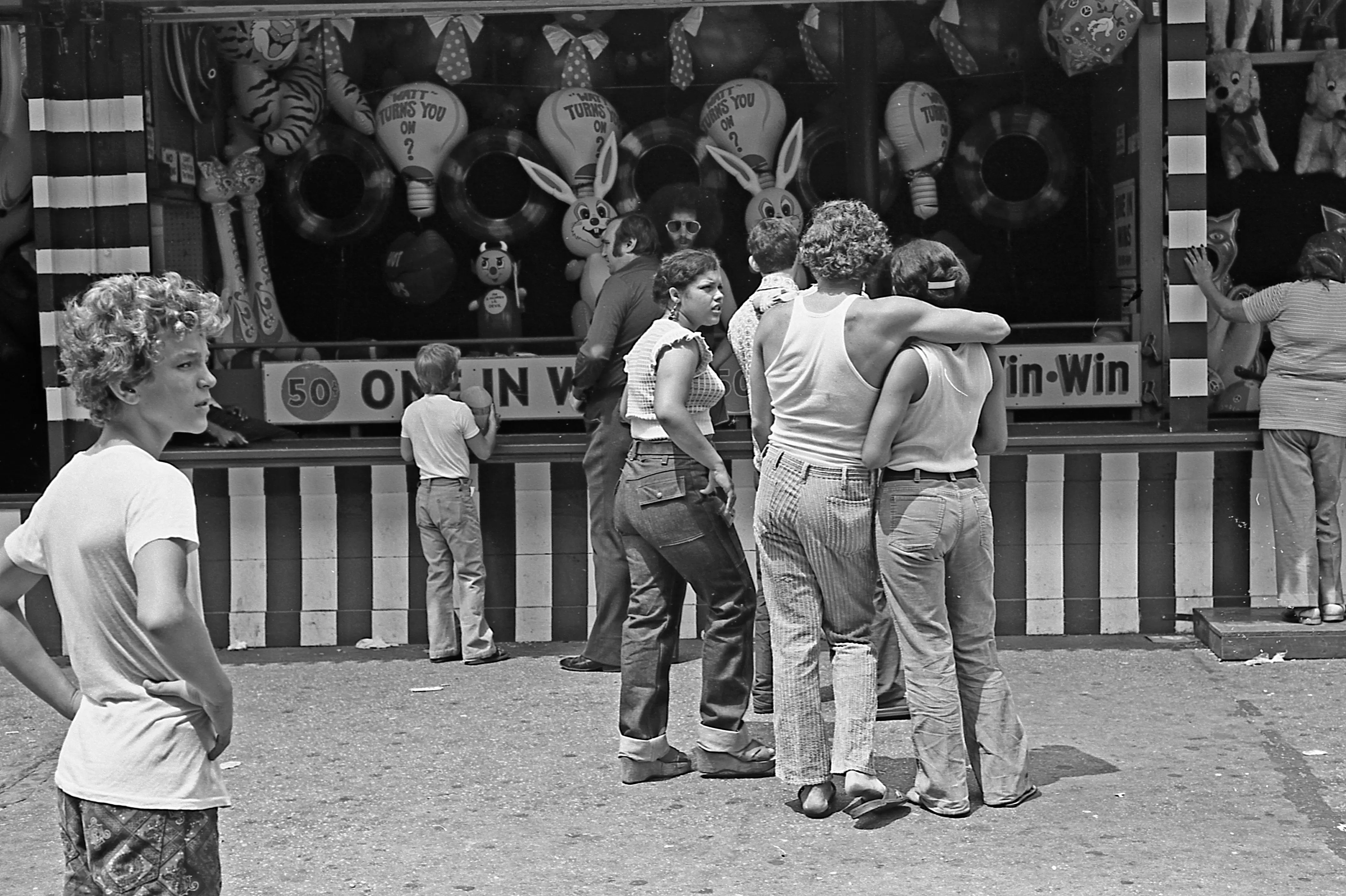 View of a group of people in front of a gaming booth at Coney Island's Astroland Park, Brooklyn, New York, New York, July 22, 1973.